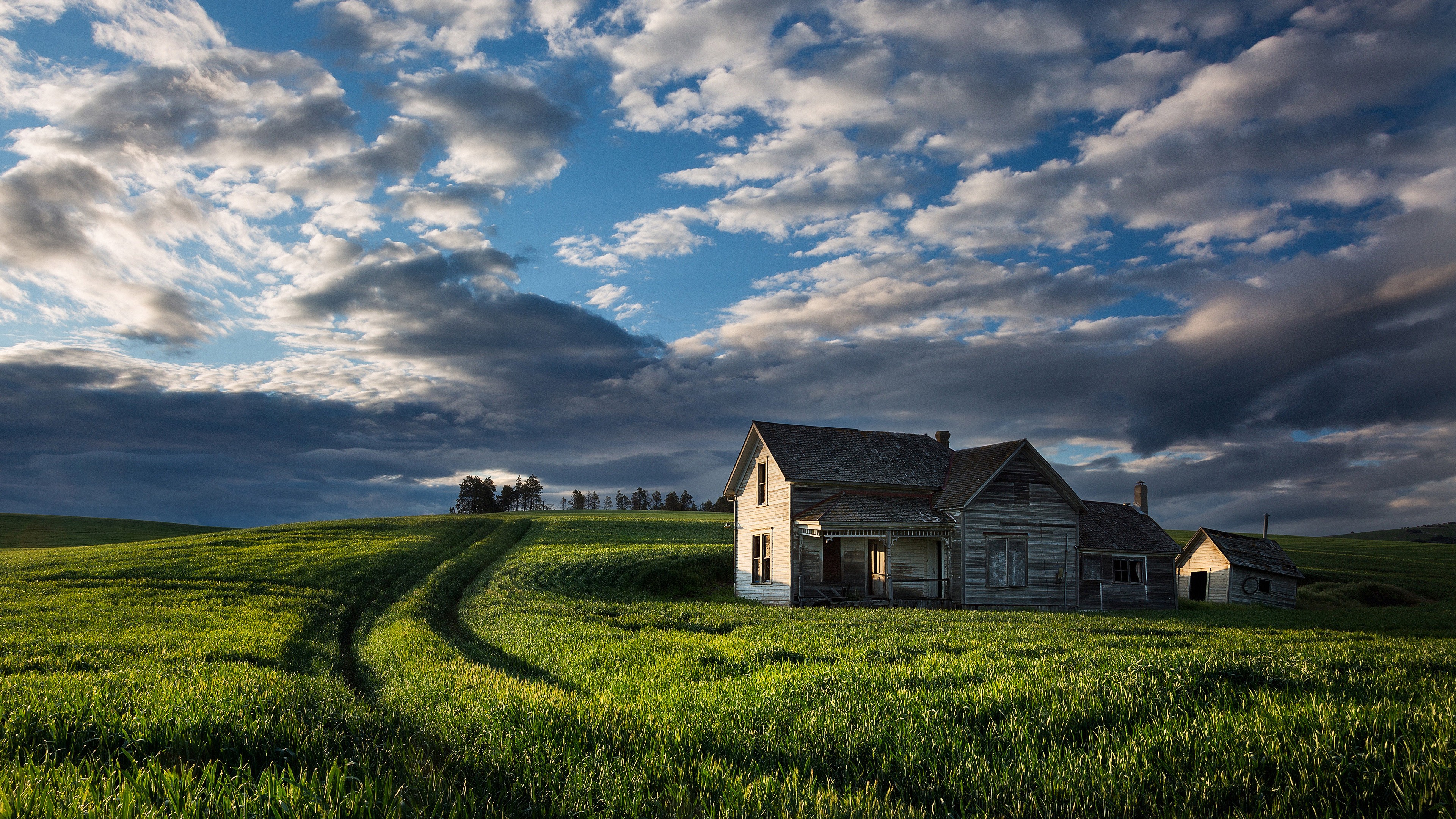 Abandoned farmhouse in a green field under a cloudy sky HD Wallpaper