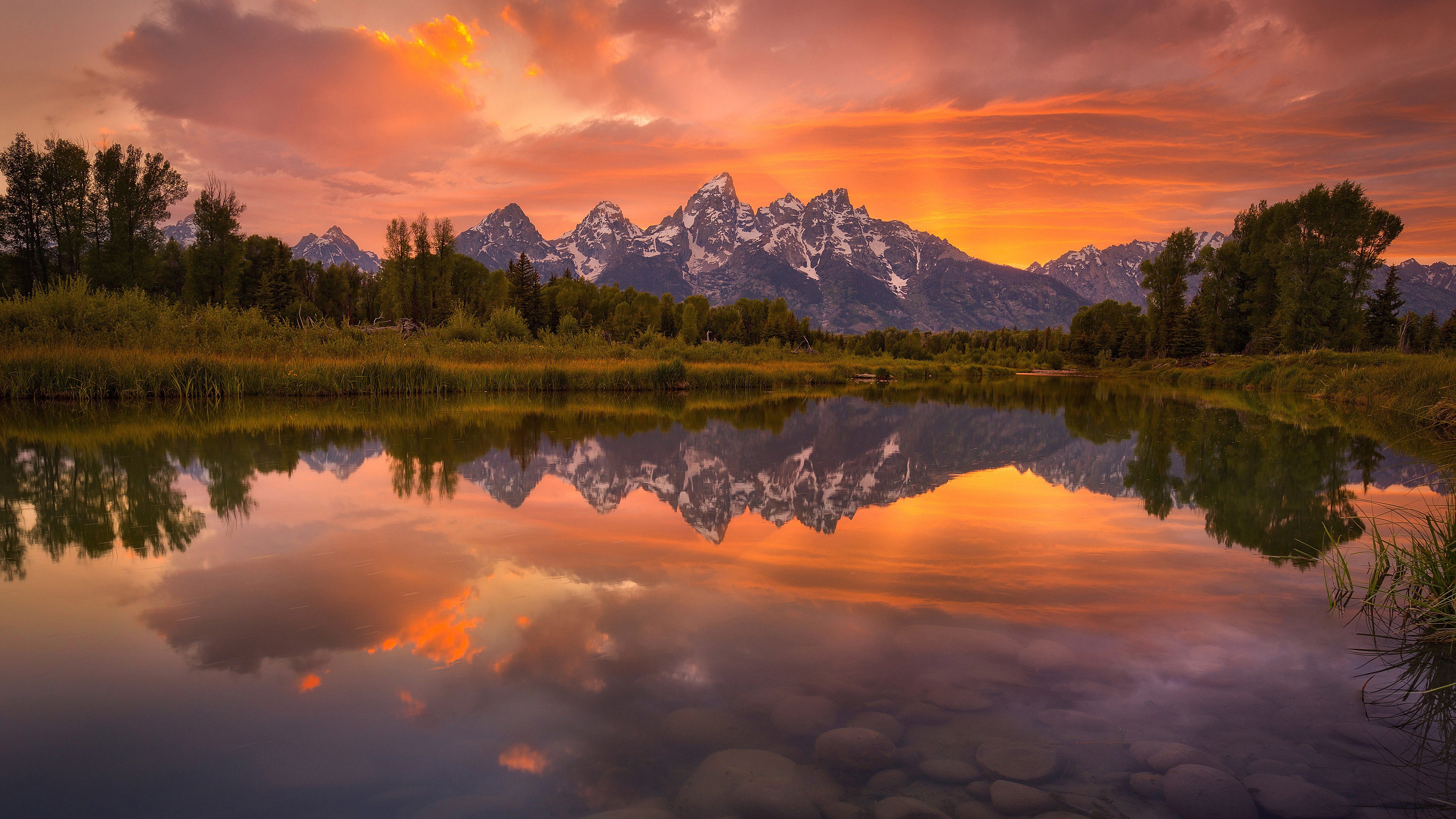 Sunset over the Teton Mountains reflected in a calm lake HD Wallpaper