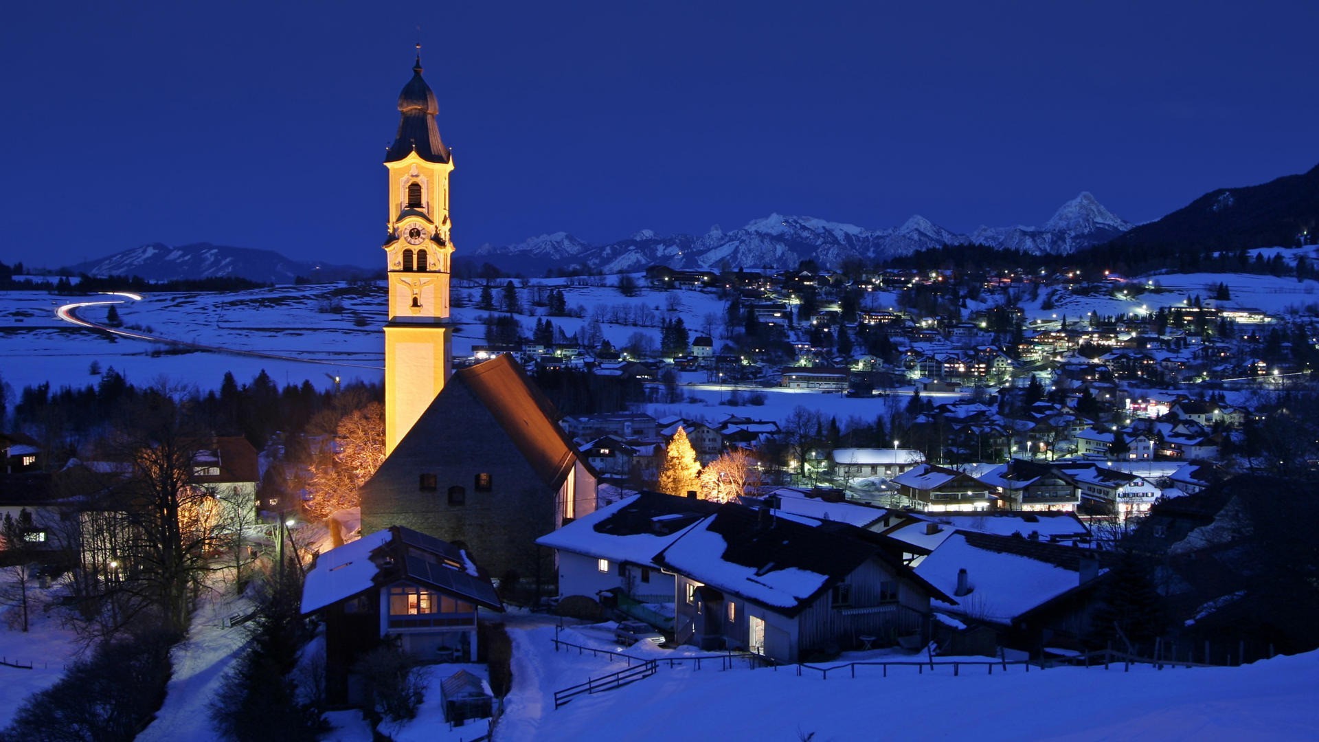 Snowy village with church tower at night HD Wallpaper