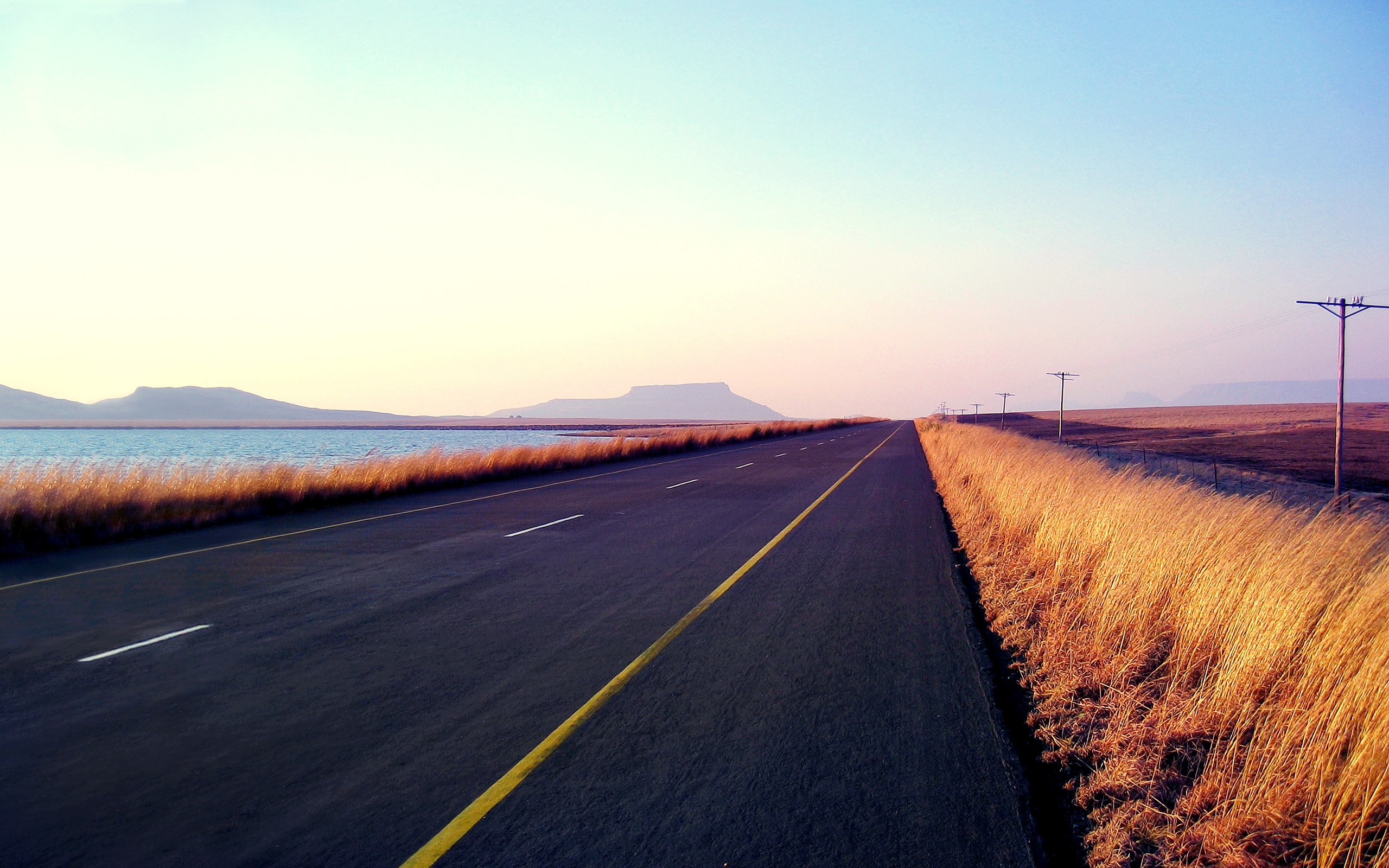 Road through a landscape with power lines HD Wallpaper