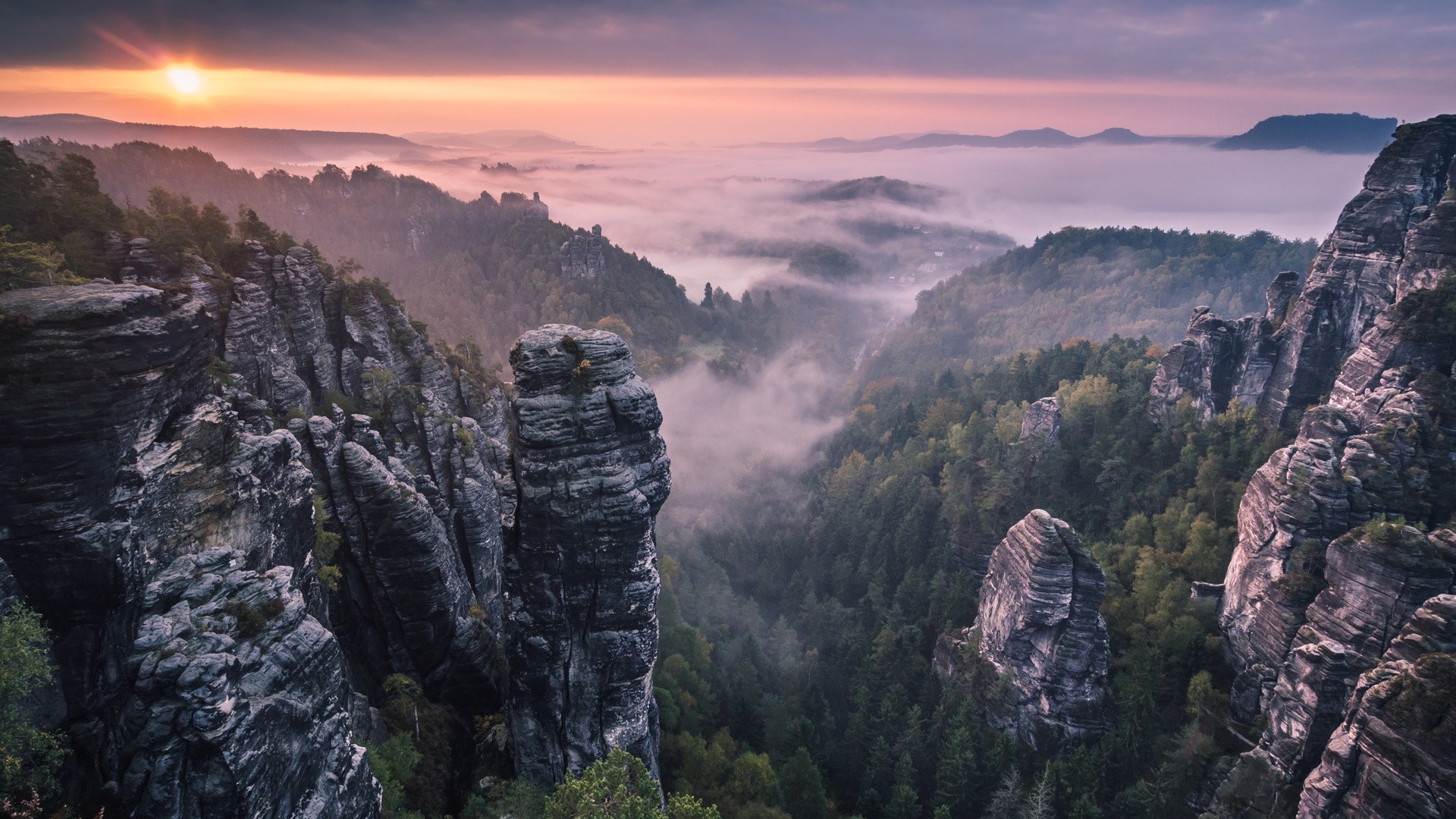 Misty valley with rock formations at sunrise HD Wallpaper