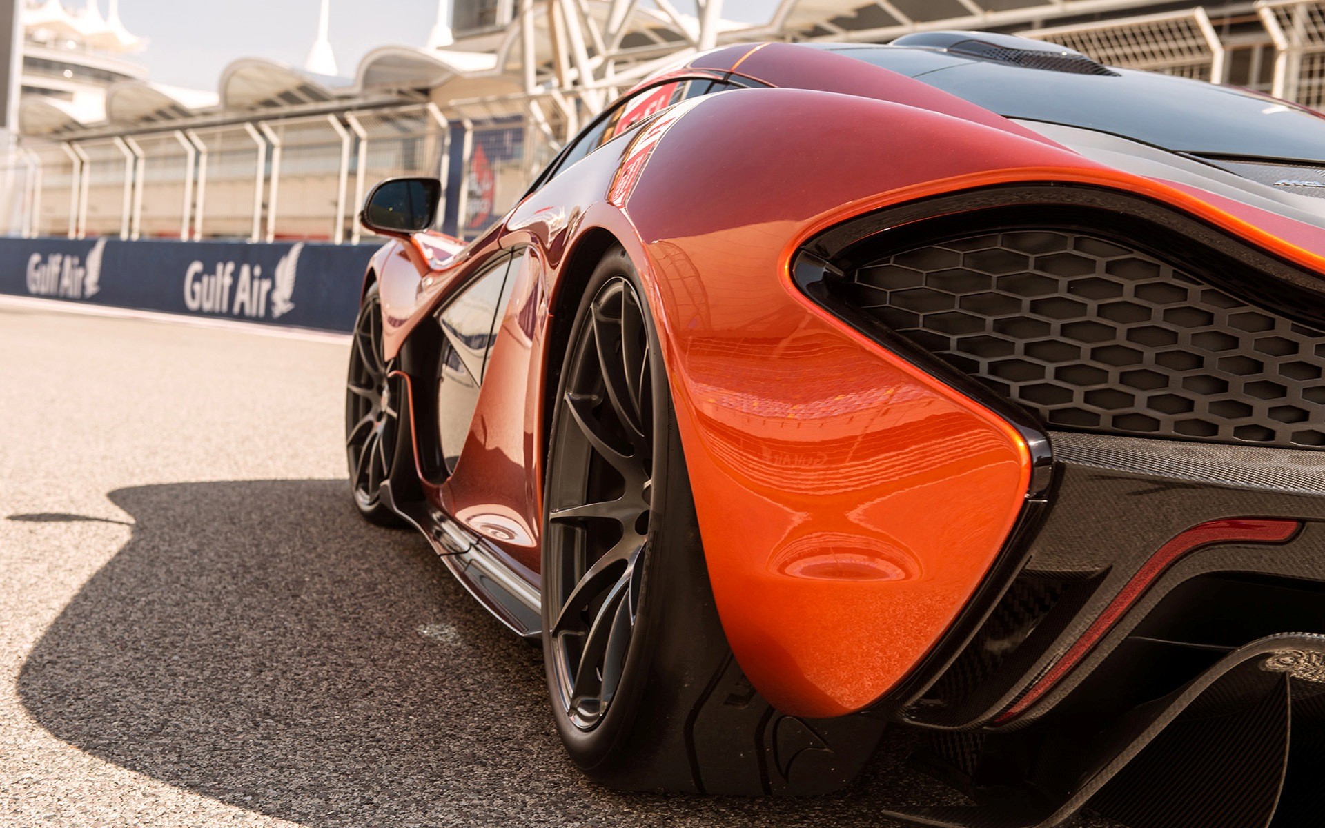 Orange McLaren P1 sports car on a race track HD Wallpaper