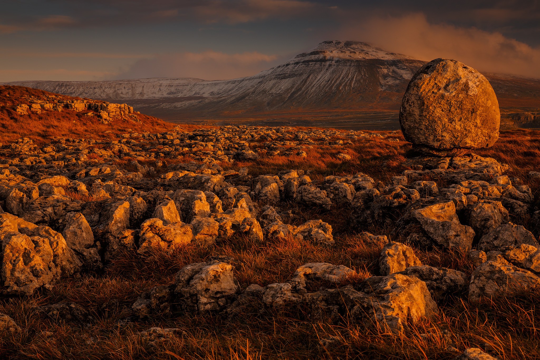 Balanced rock on a rocky landscape with snow-capped mountains HD Wallpaper