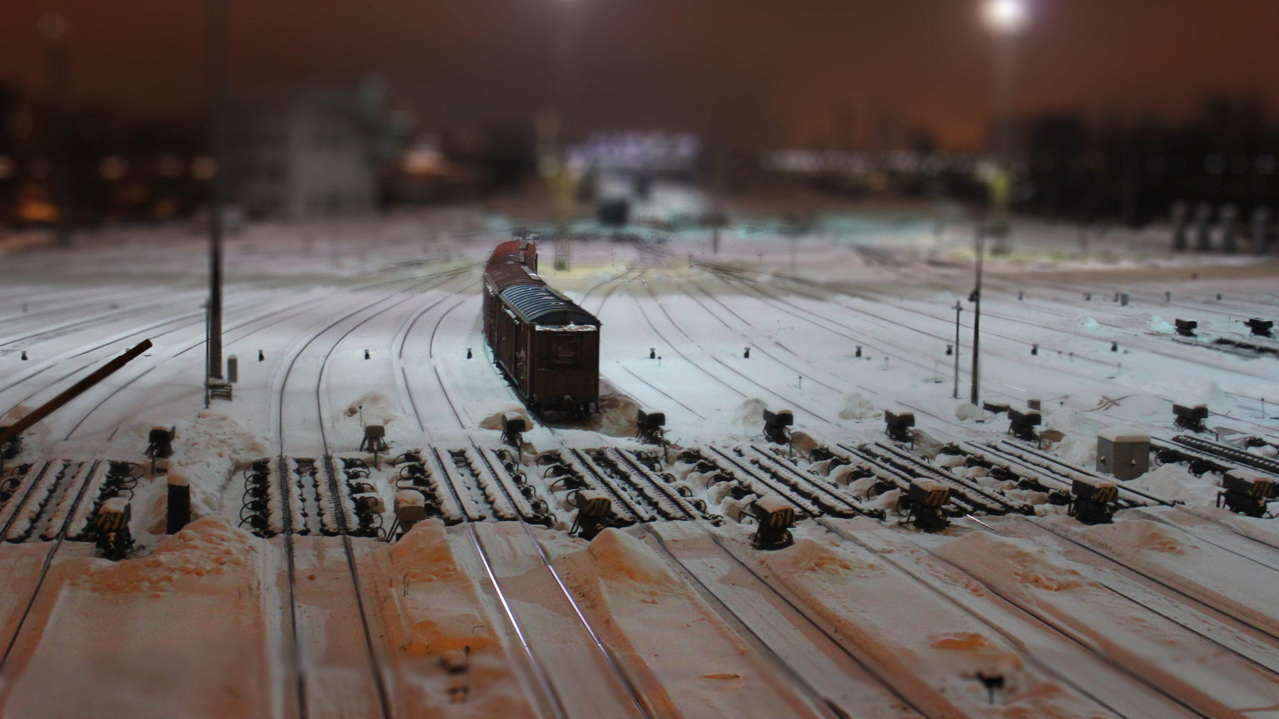 Train in a snowy rail yard with tilt-shift effect HD Wallpaper