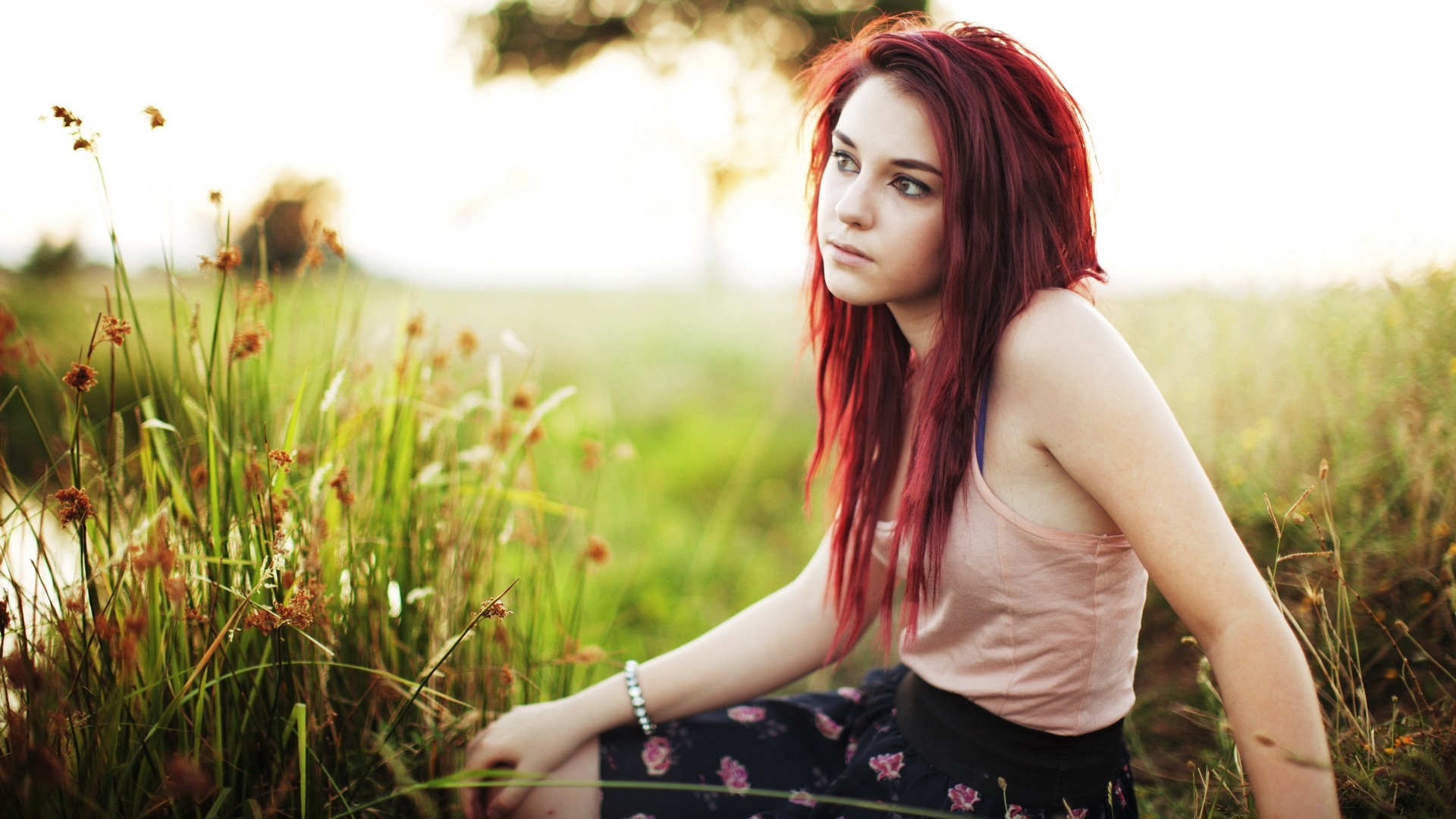 Redhead woman sitting in a grassy field HD Wallpaper