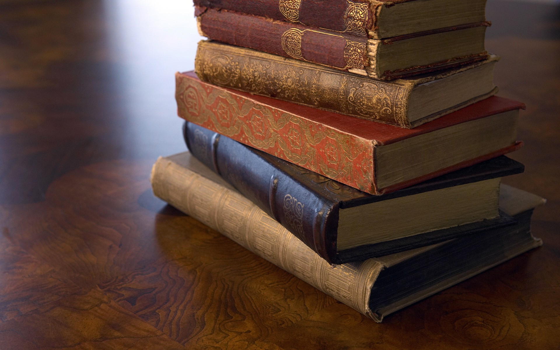 Stack of old books on a wooden surface HD Wallpaper