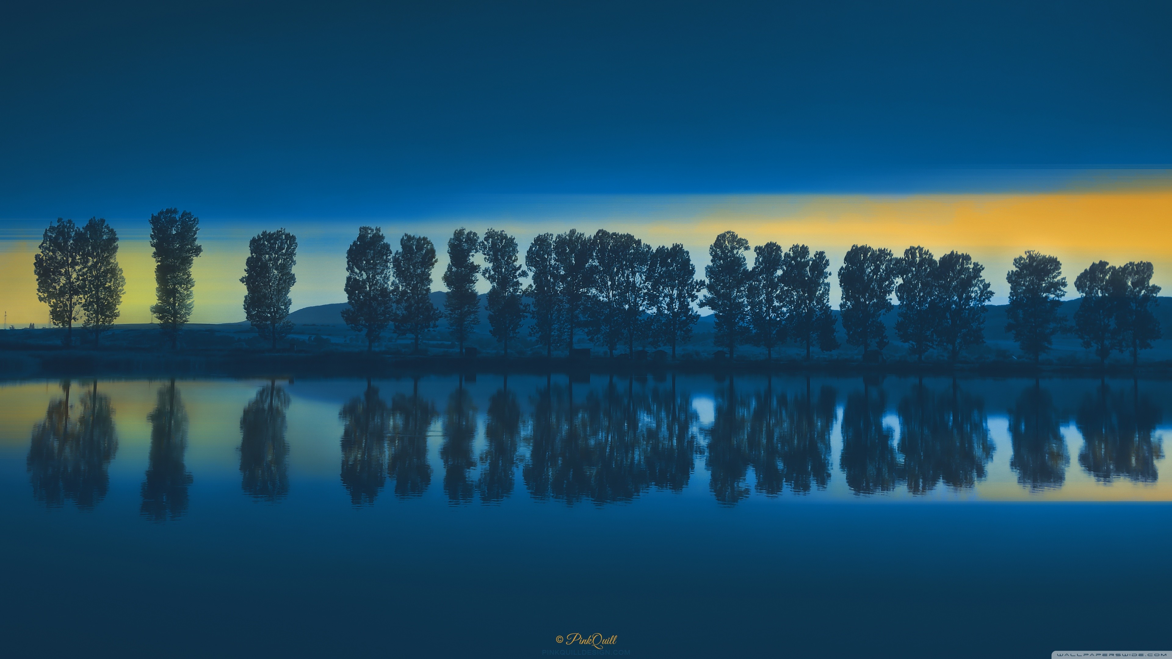 Trees reflected in a lake at sunset HD Wallpaper