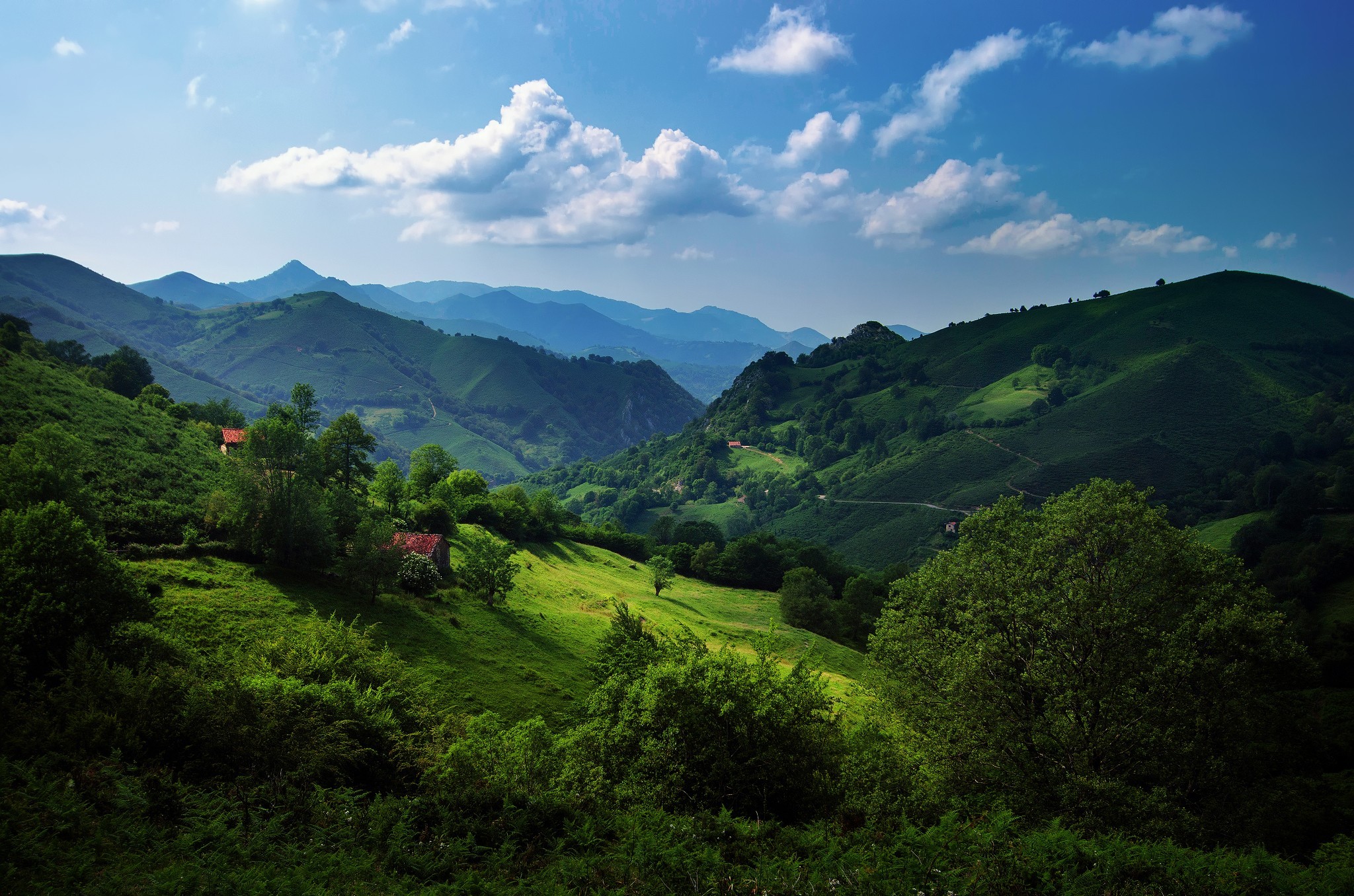 Green rolling hills and mountains in Spain under a blue sky HD Wallpaper