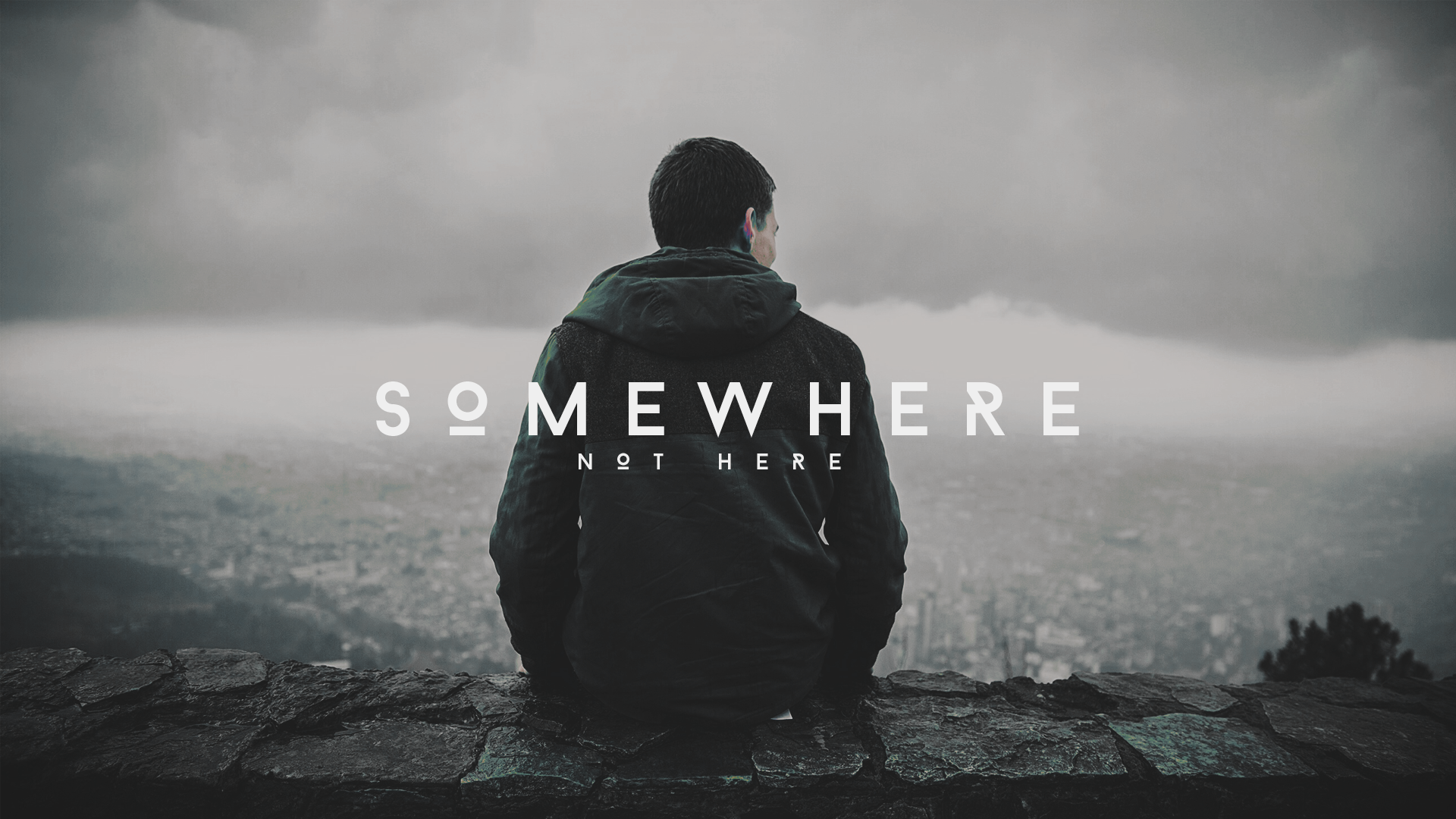 Man sitting on a wall overlooking a city HD Wallpaper