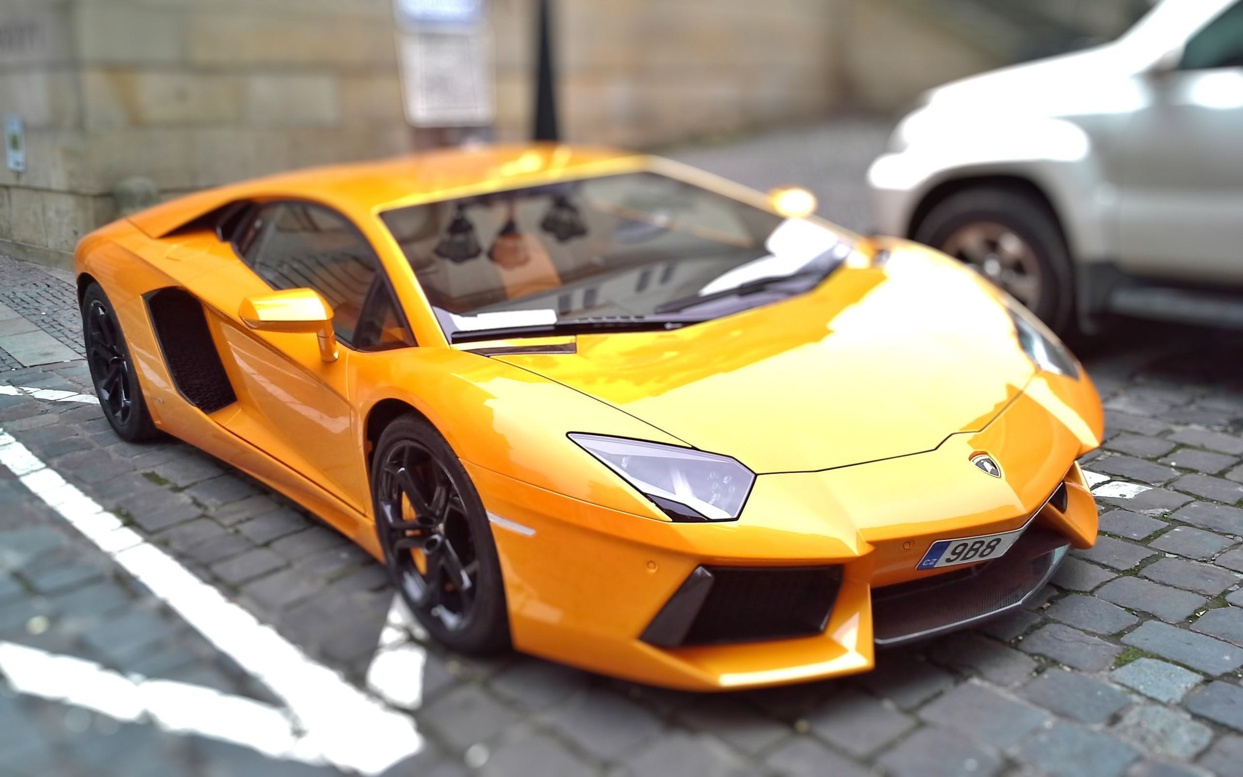 Orange Lamborghini Aventador parked on cobblestone street HD Wallpaper