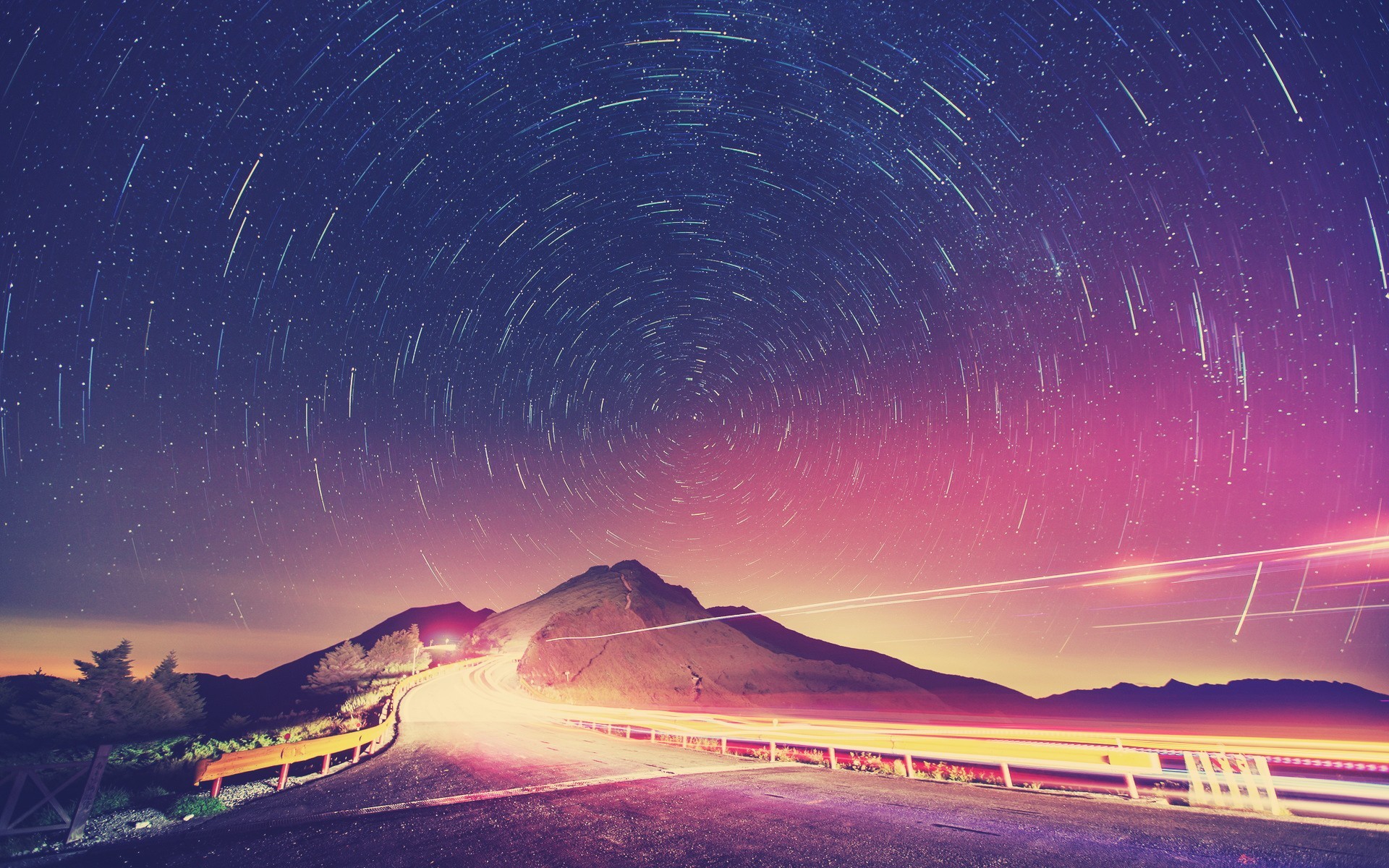 Star trails over a mountain road at night HD Wallpaper