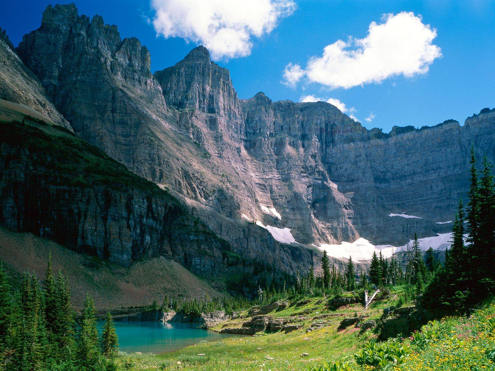Majestic mountains overlooking a turquoise lake in Glacier National Park HD Wallpaper