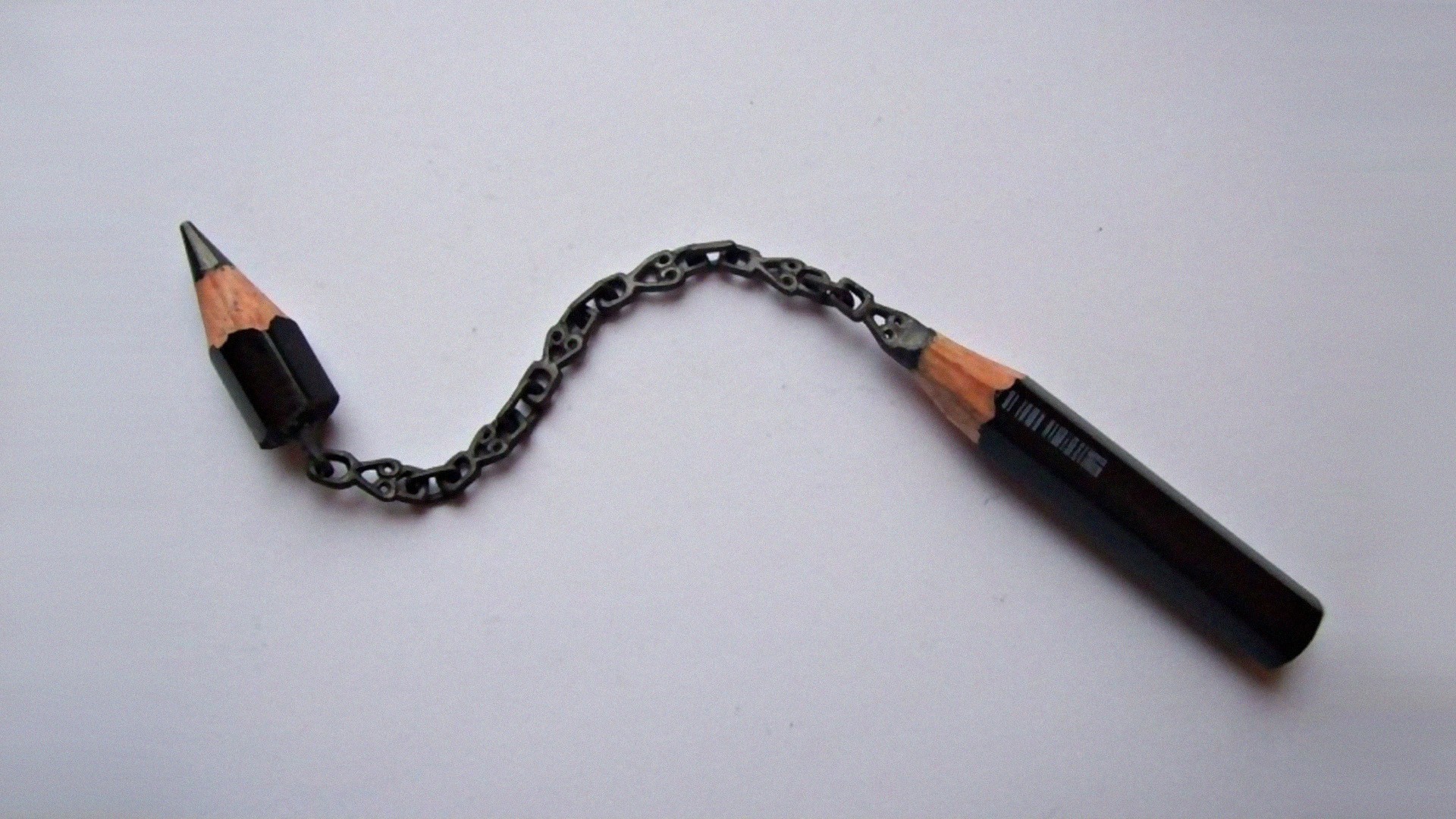 Pencil sculpture with chain on a white background HD Wallpaper