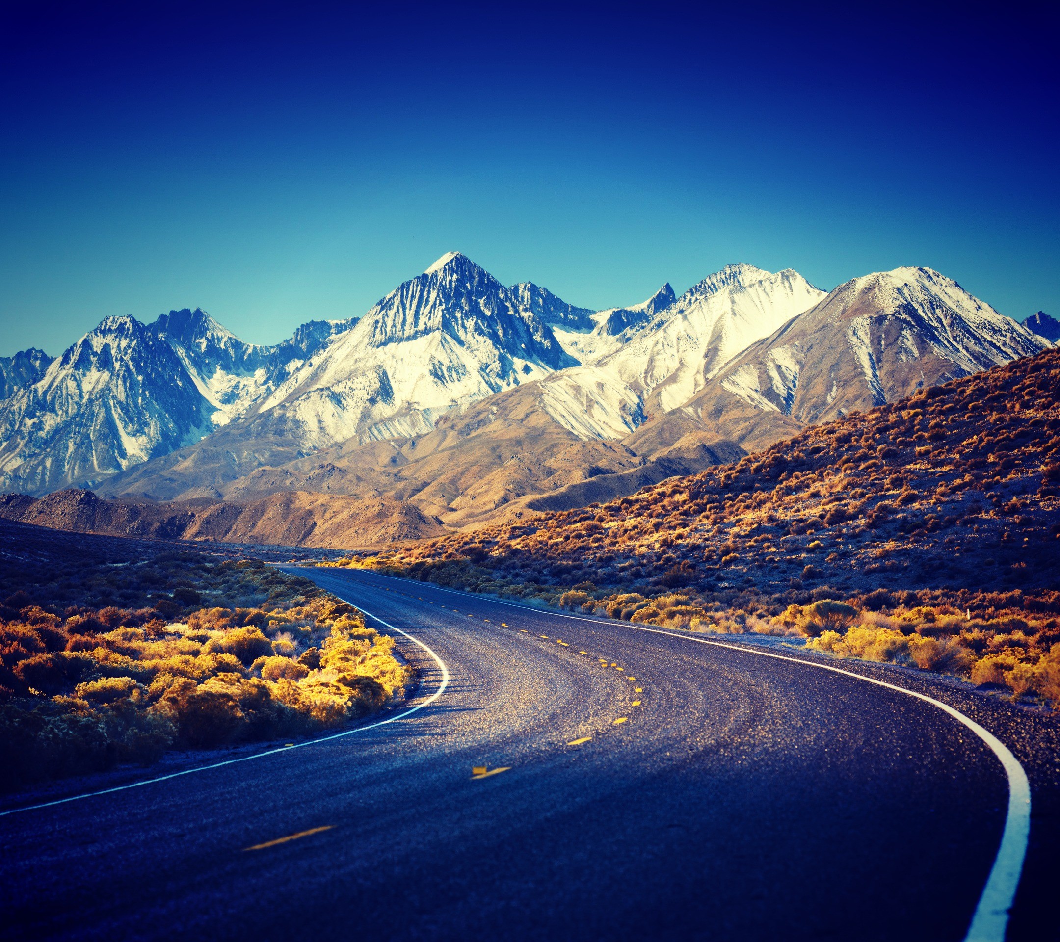 Road leading to snow-capped Sierra Nevada mountains HD Wallpaper