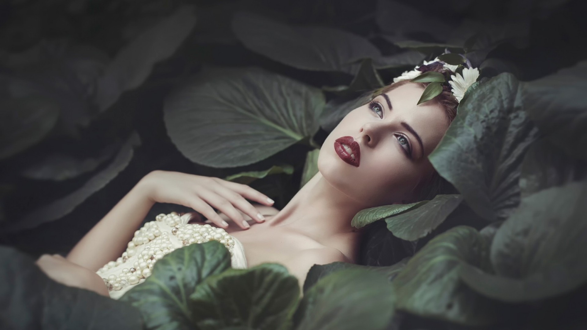 Woman with red lipstick and pearls among leaves HD Wallpaper