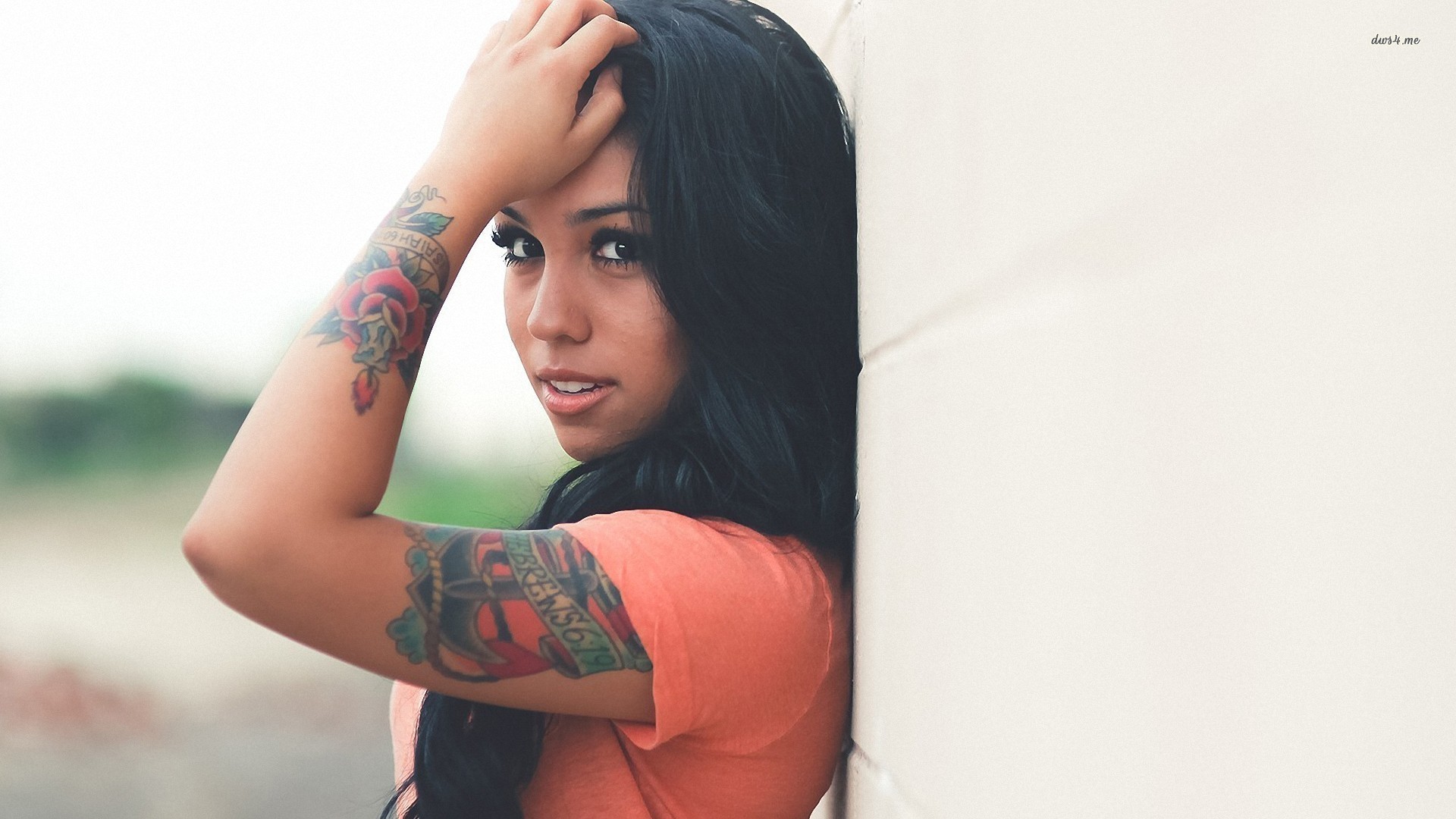 Woman with tattoos leaning against a wall HD Wallpaper
