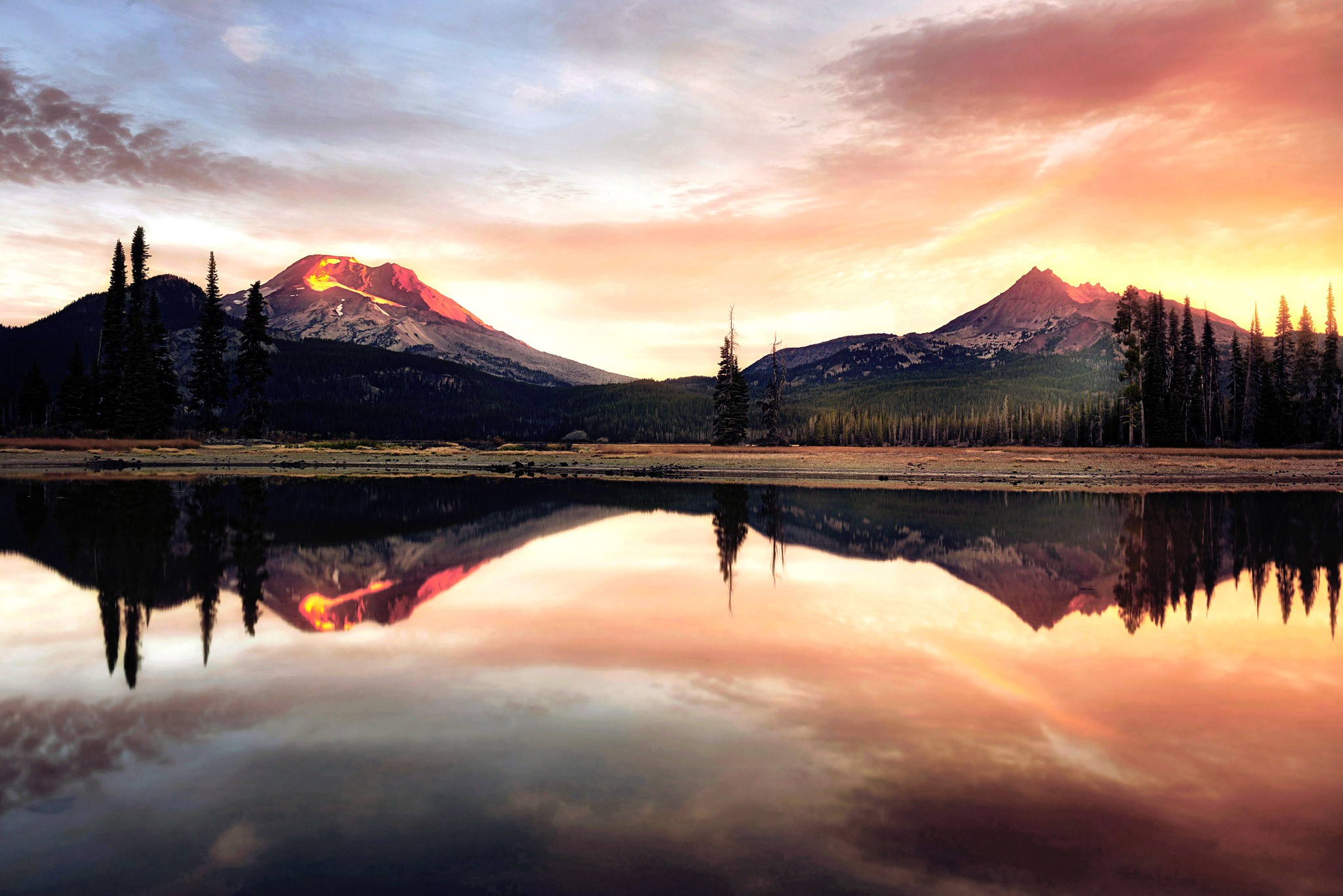 Mountains reflected in a lake at sunset HD Wallpaper