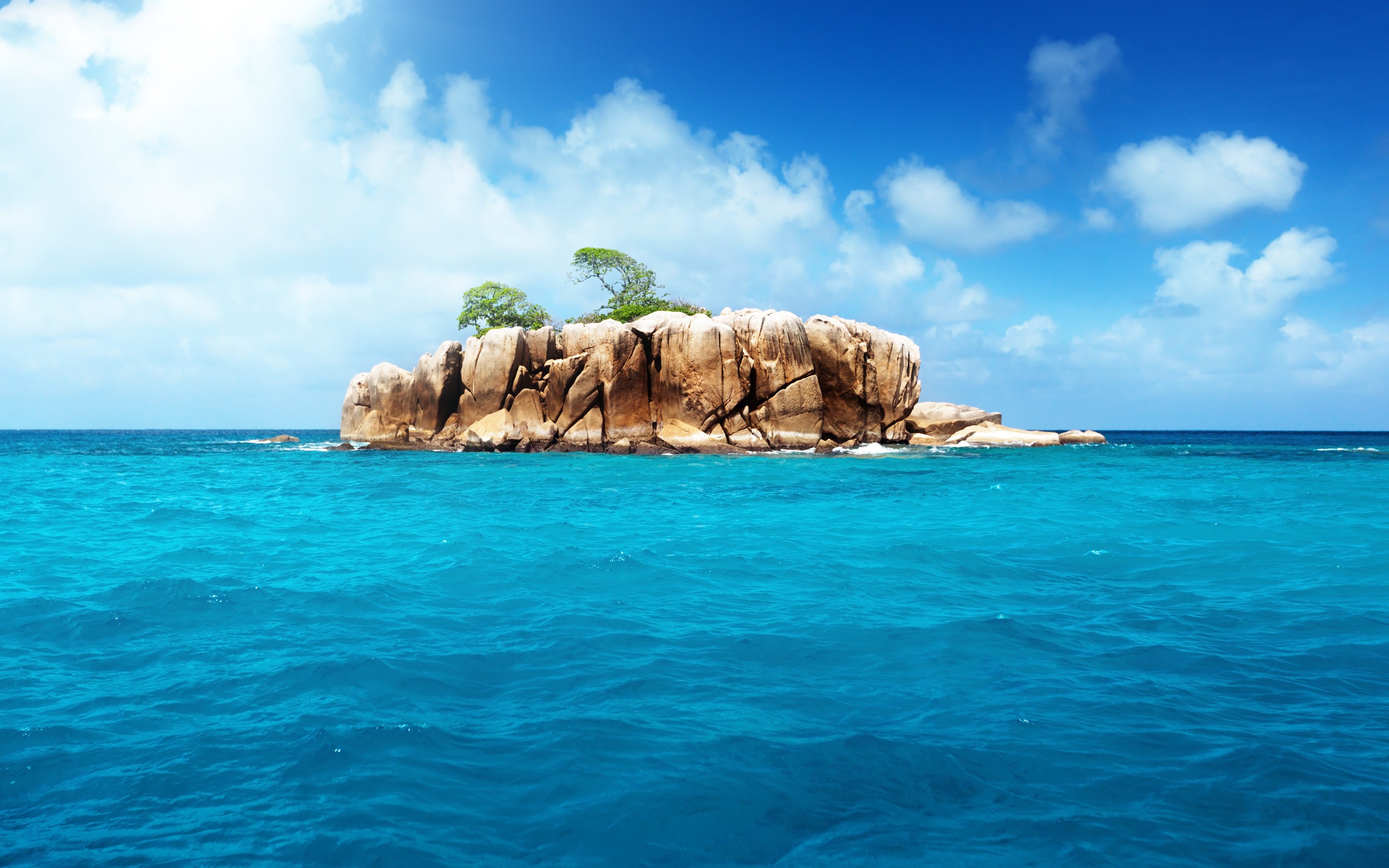 Rocky island in turquoise ocean under blue sky HD Wallpaper