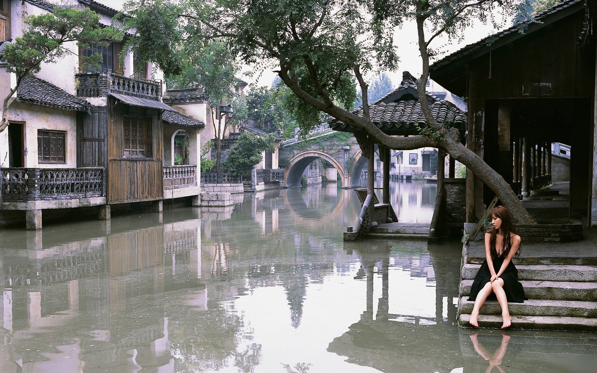 Woman in black dress sitting by a canal in a Japanese town HD Wallpaper