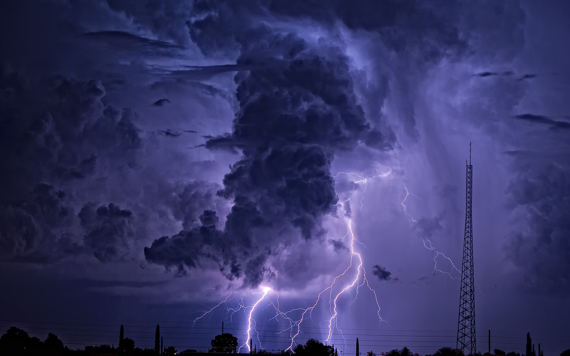 Lightning strikes during a powerful thunderstorm over a landscape. HD Wallpaper