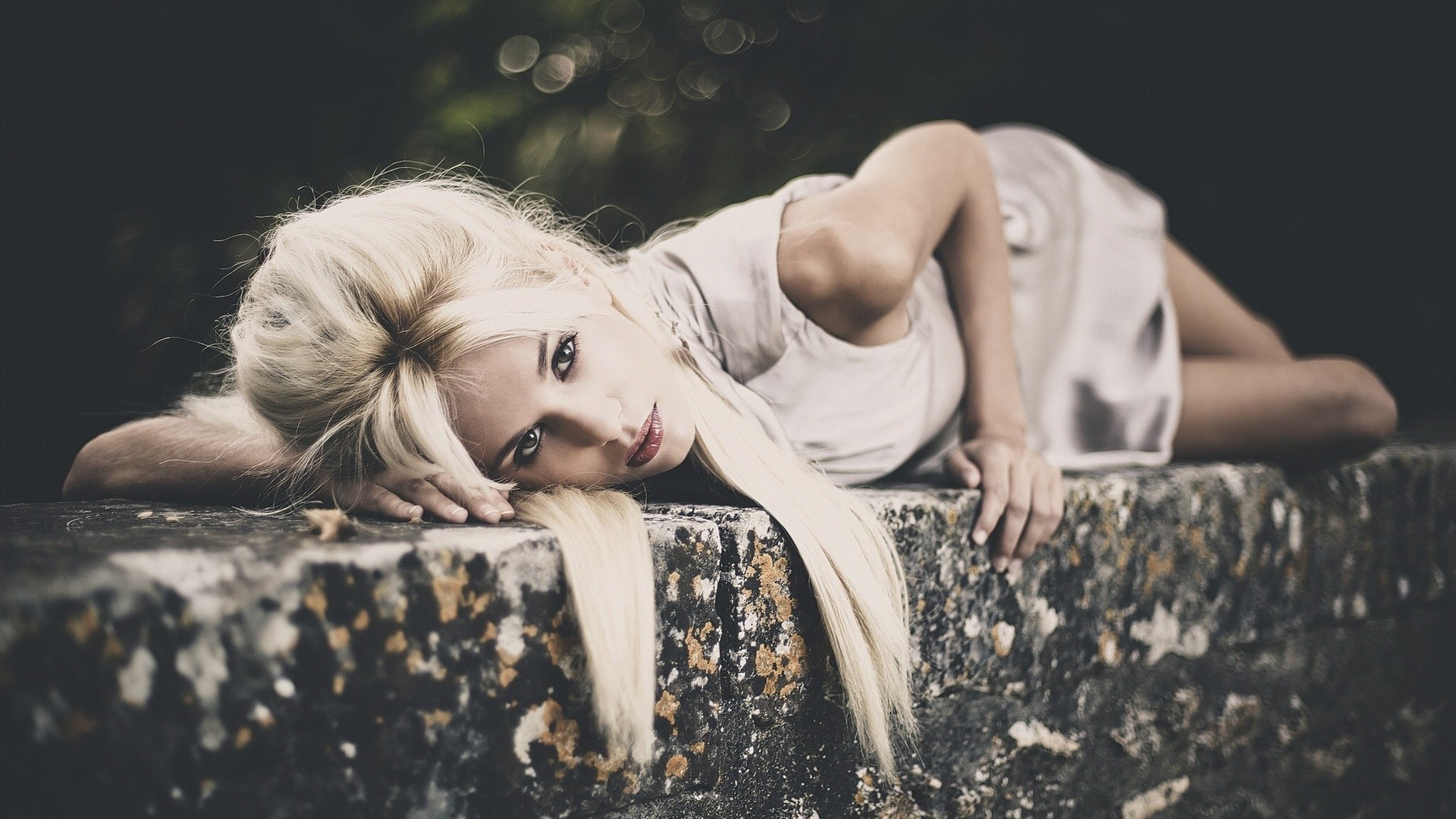 Blonde woman lying on a stone wall HD Wallpaper