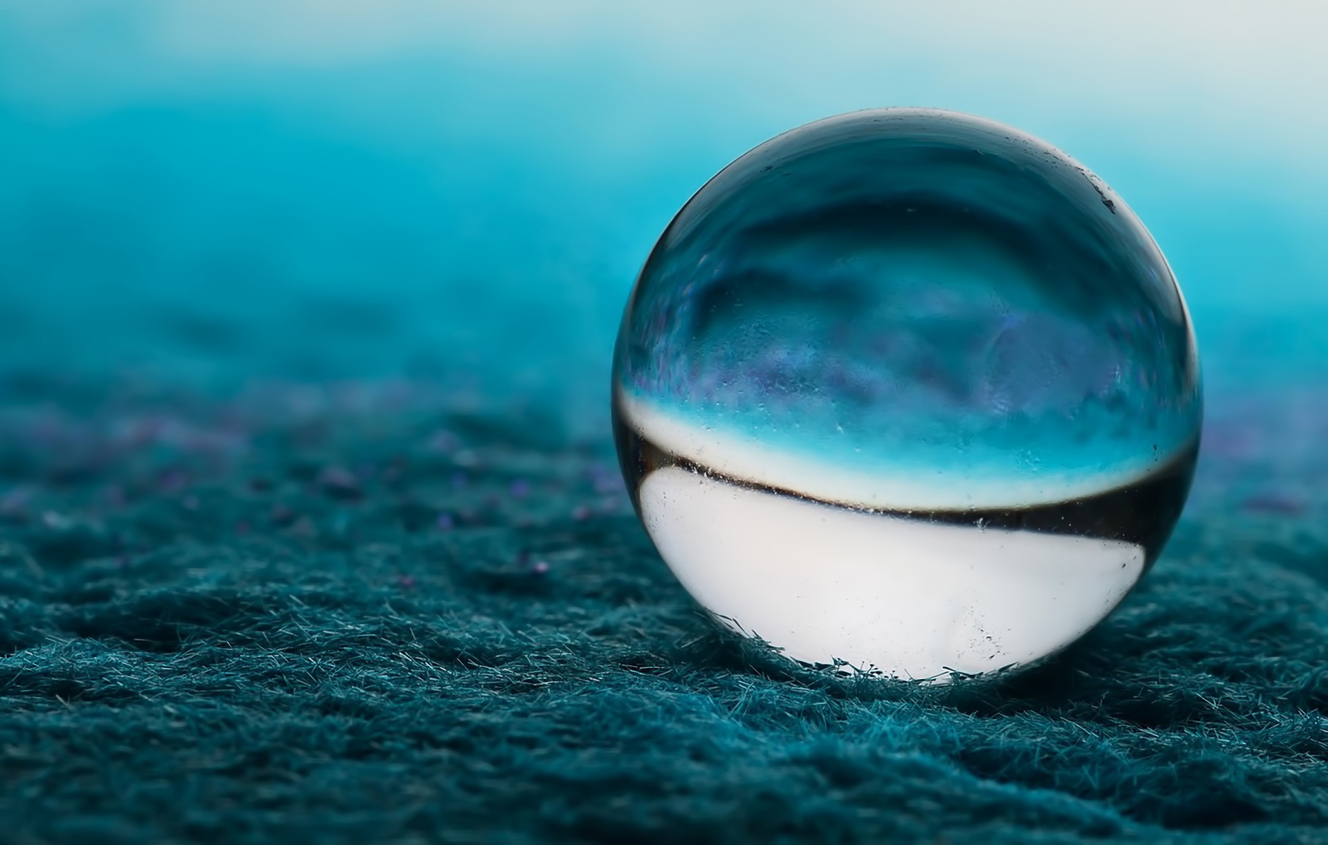 Macro photography of a glass sphere on a textured surface HD Wallpaper