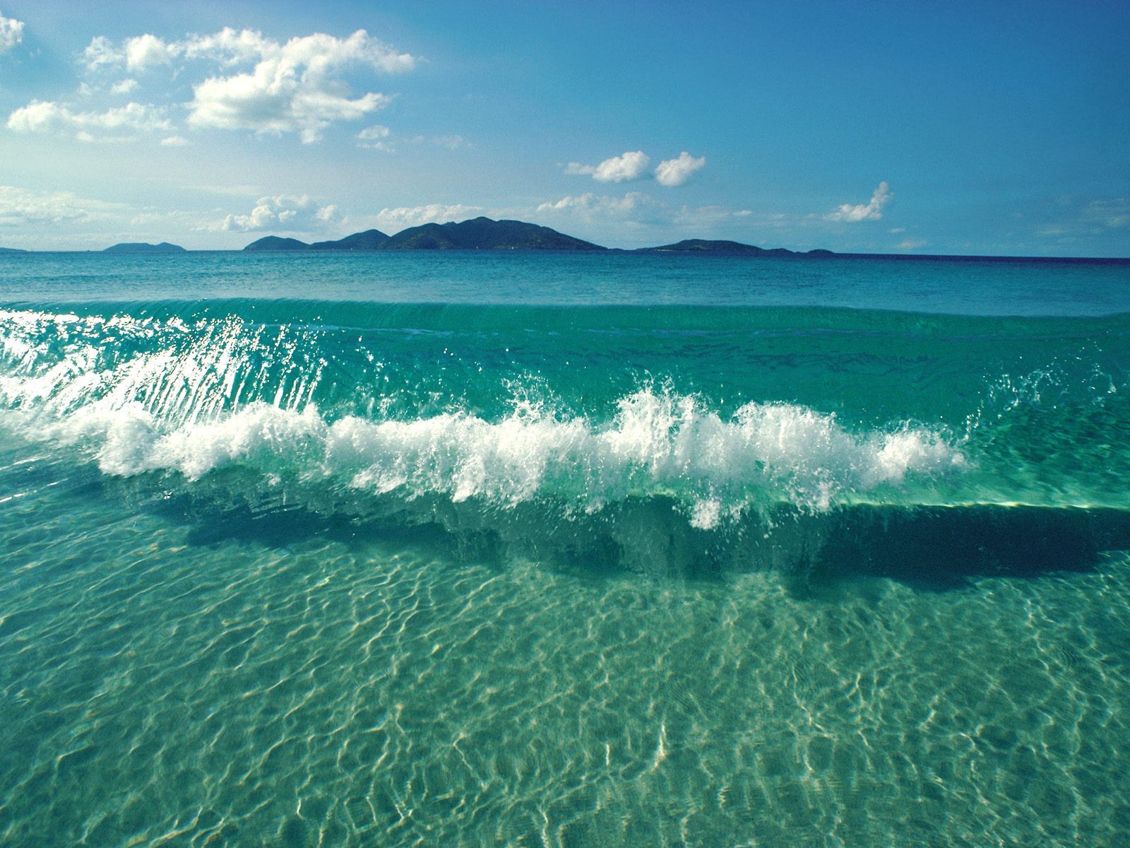 Turquoise ocean wave with islands in the distance HD Wallpaper