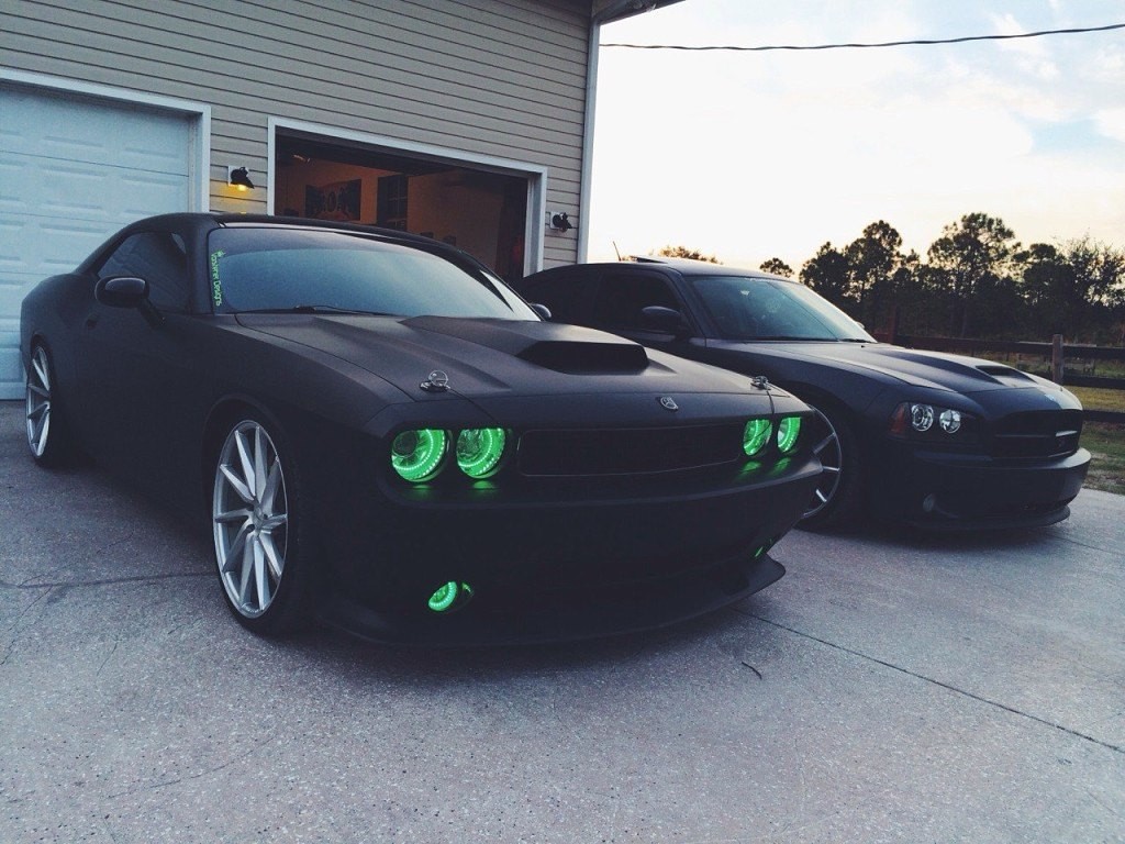 Two Dodge muscle cars parked outside a garage HD Wallpaper