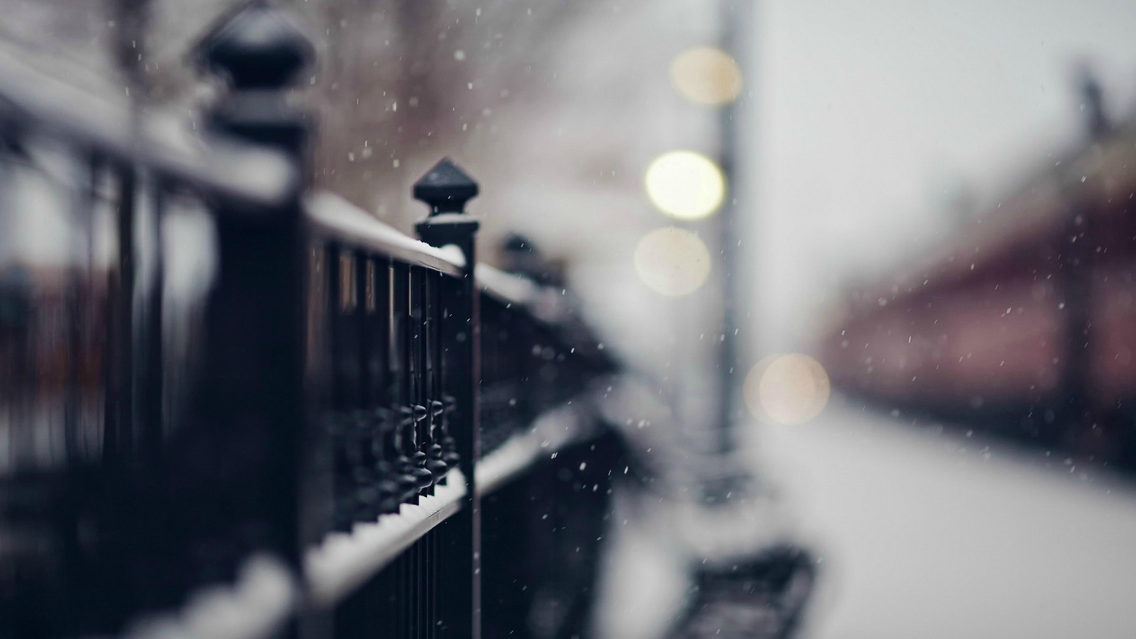 Snow falling on a fence with bokeh lights HD Wallpaper