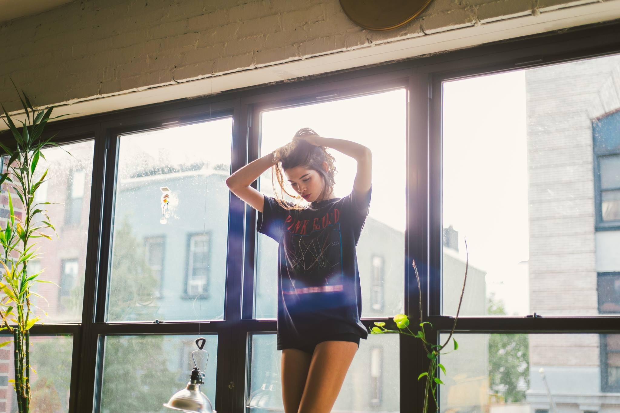 Woman with hands in hair in front of window HD Wallpaper