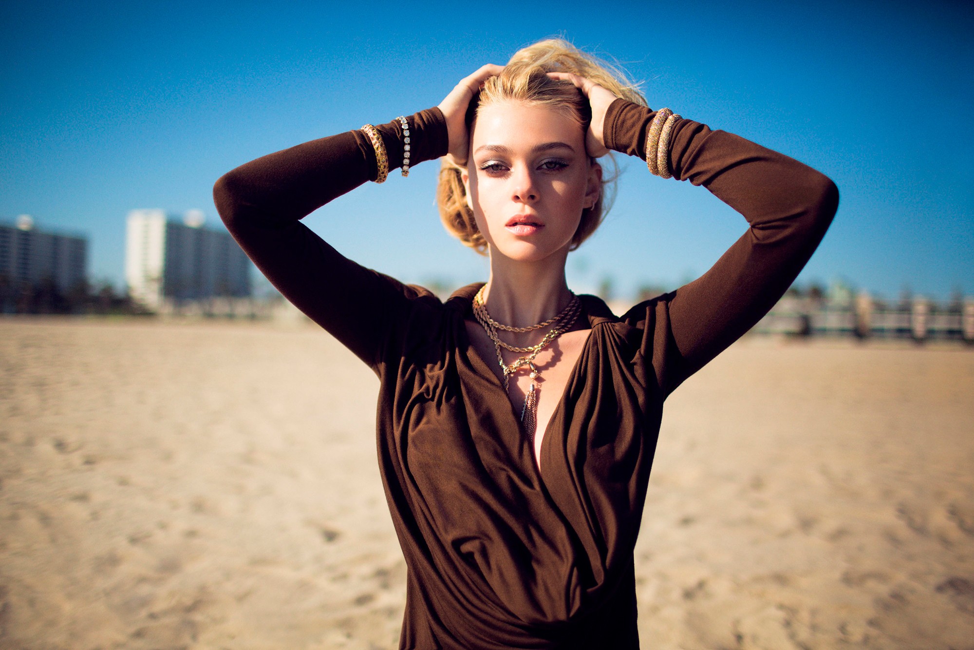 Nicola Peltz with hands on head on a beach HD Wallpaper