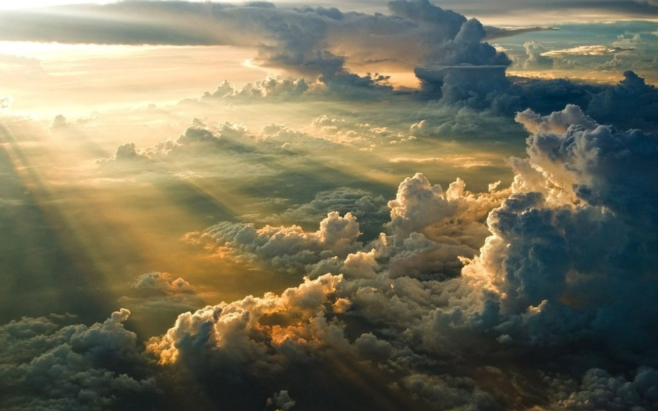 Sun rays shining through dramatic clouds from above HD Wallpaper