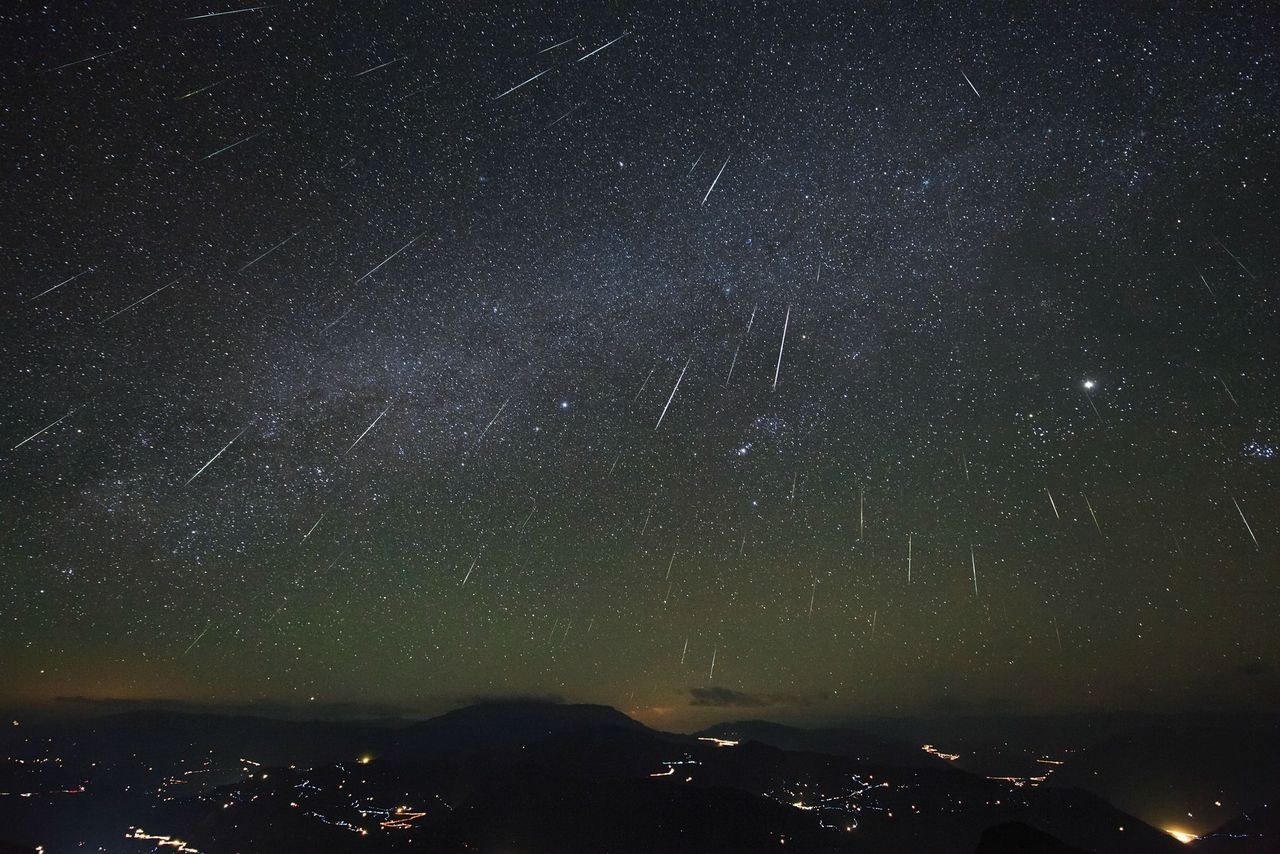 Night sky filled with shooting stars over a city HD Wallpaper