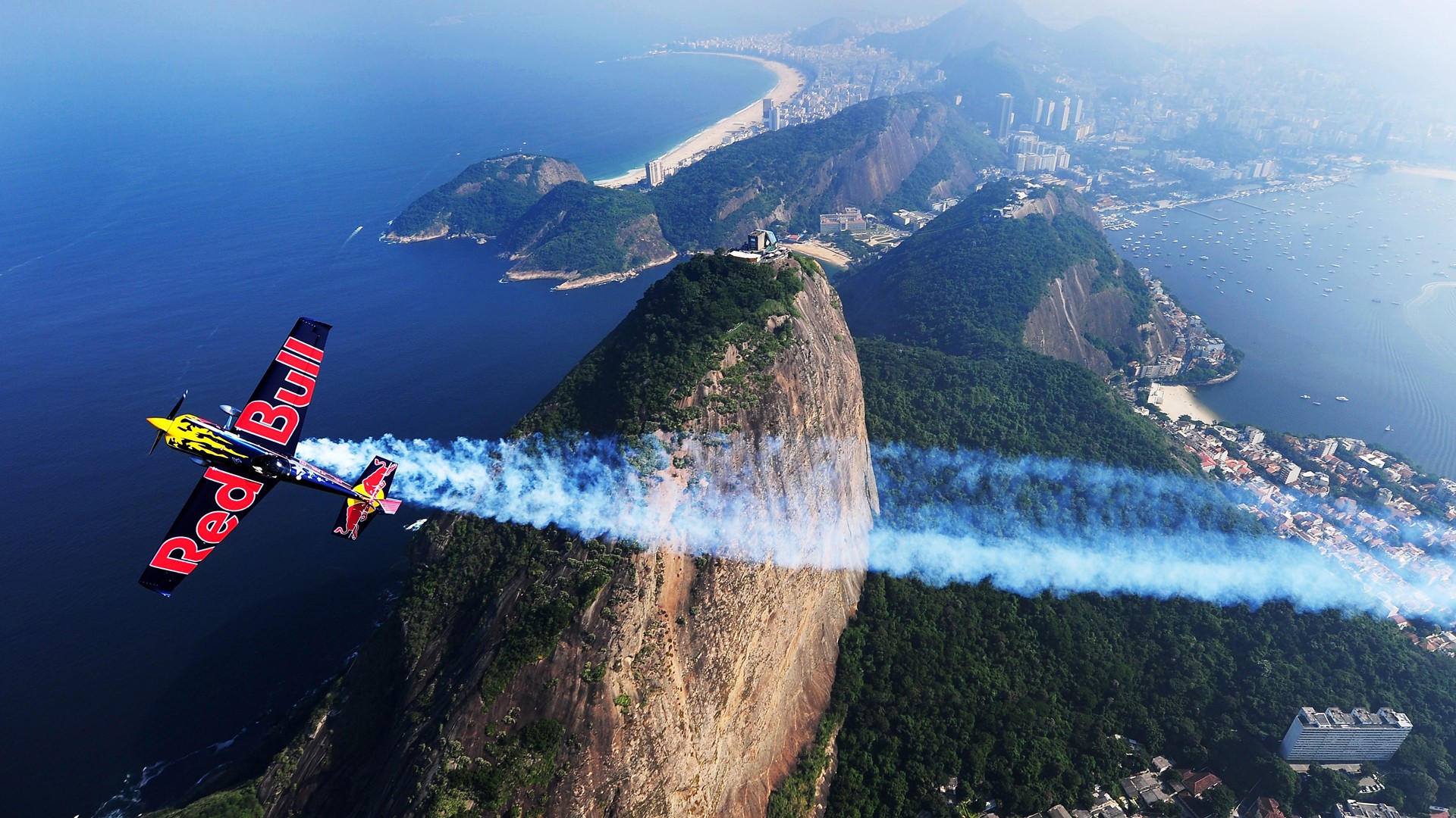 Red Bull airplane flying over Rio de Janeiro mountains HD Wallpaper