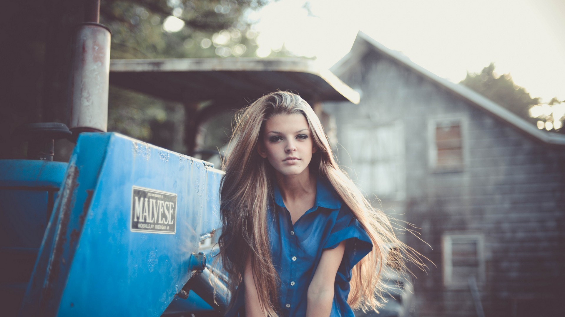 Woman in blue shirt next to a blue tractor HD Wallpaper