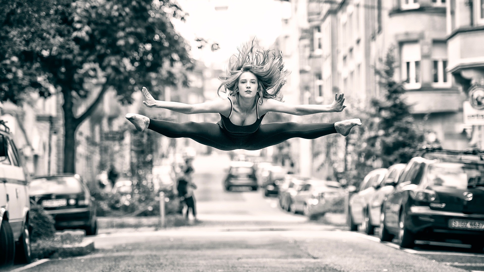 Woman performing a split jump in a city street HD Wallpaper