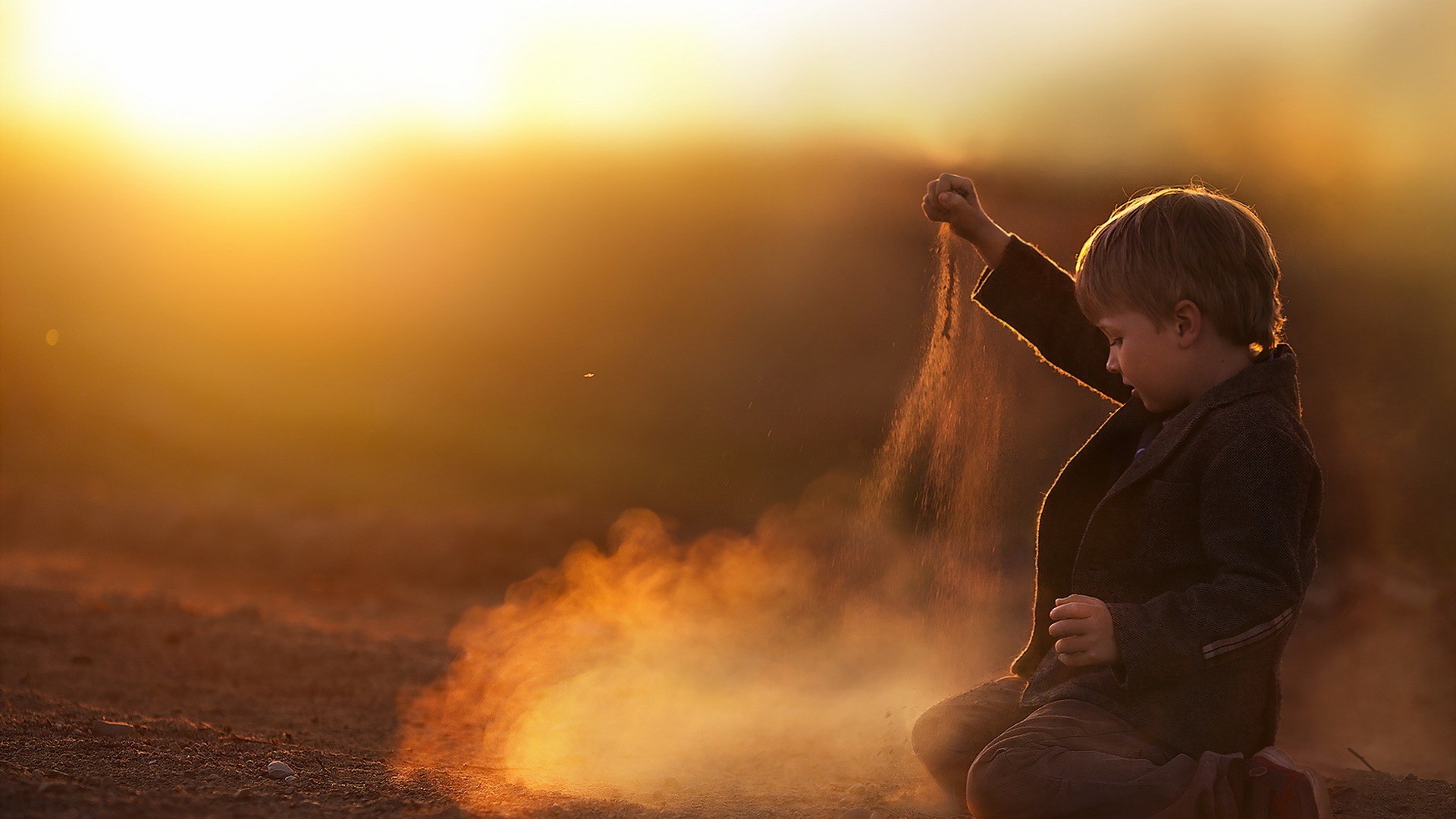 Boy playing with sand at sunset HD Wallpaper