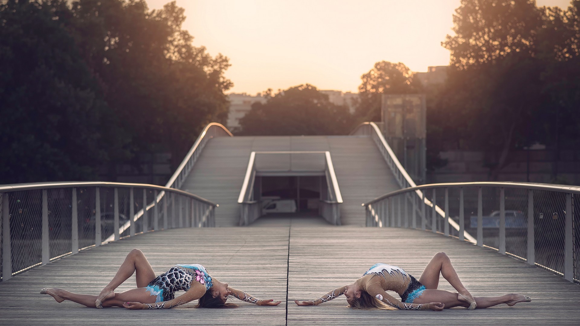 Two women in leotards on a bridge at sunset HD Wallpaper