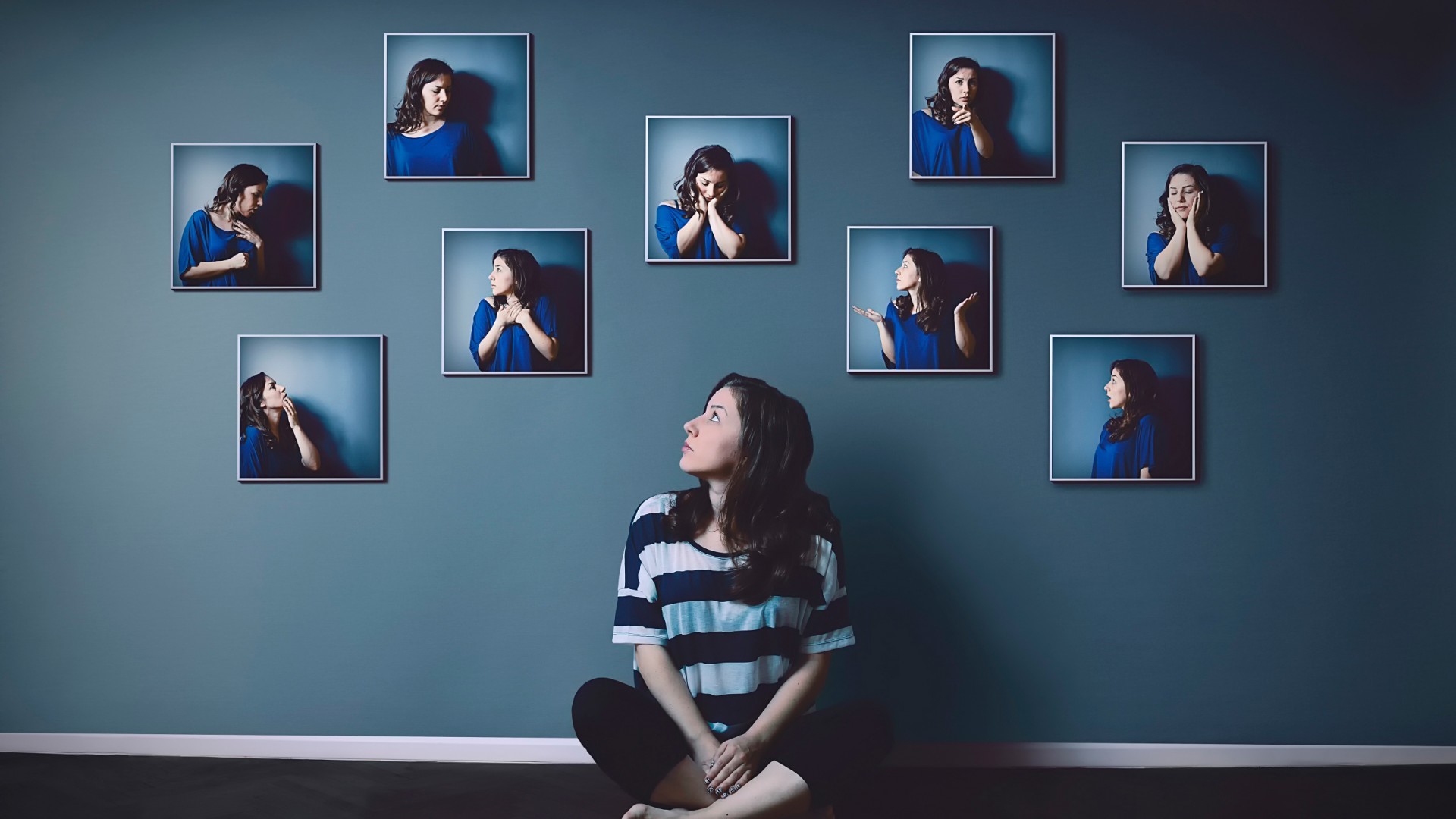Woman looking at framed photos of herself HD Wallpaper