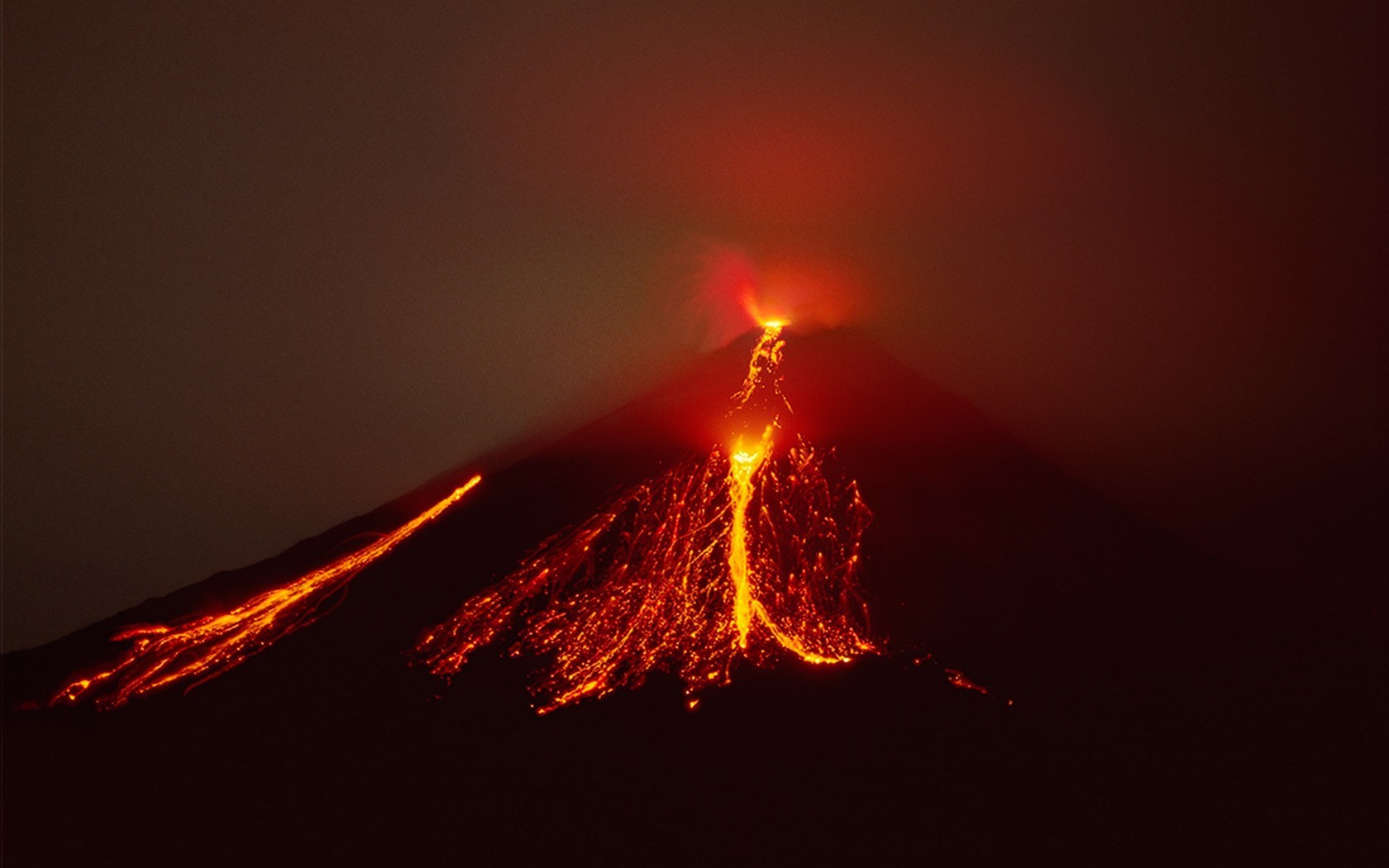 Volcano erupting with lava flows at night HD Wallpaper