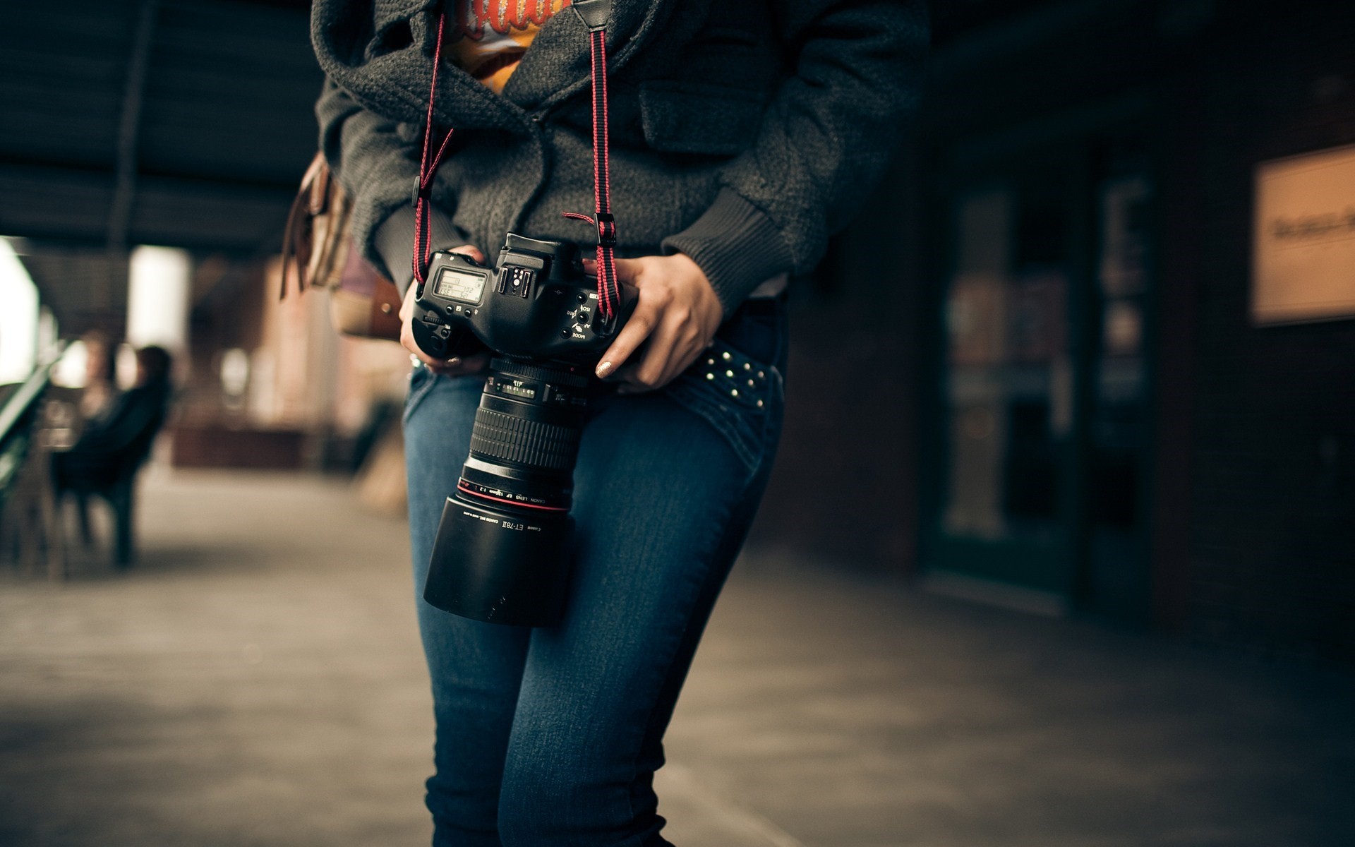 Canon DSLR camera with lens held by a person in jeans HD Wallpaper