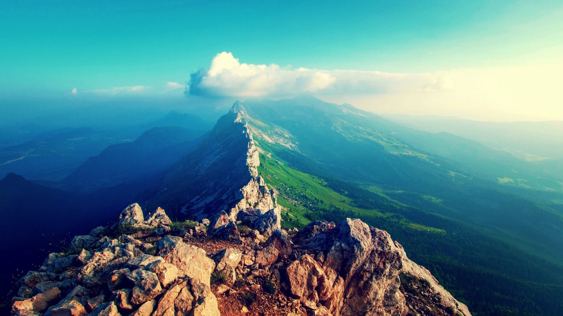 Mountains and clouds over a vast landscape HD Wallpaper