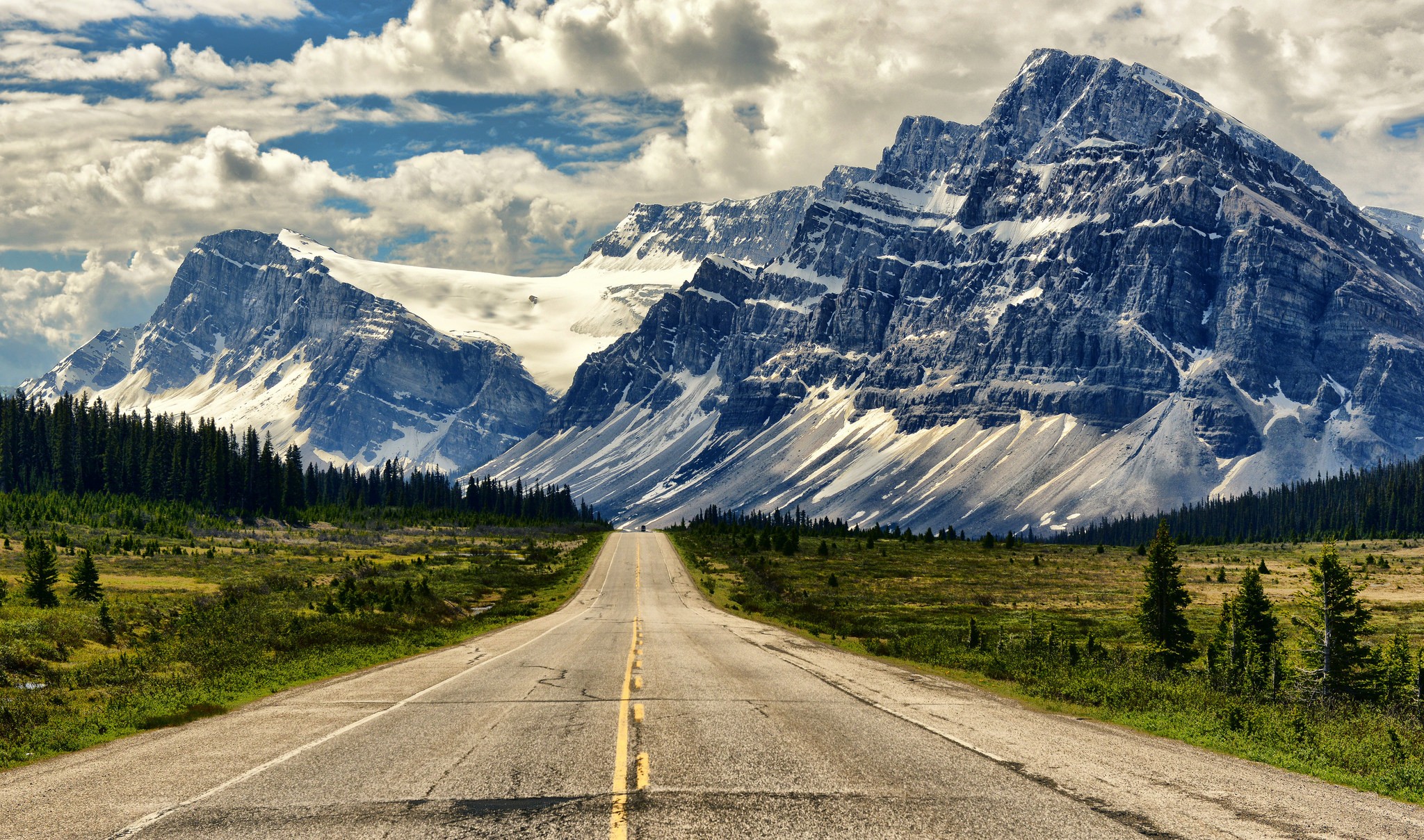Road leading to snow-capped mountains HD Wallpaper