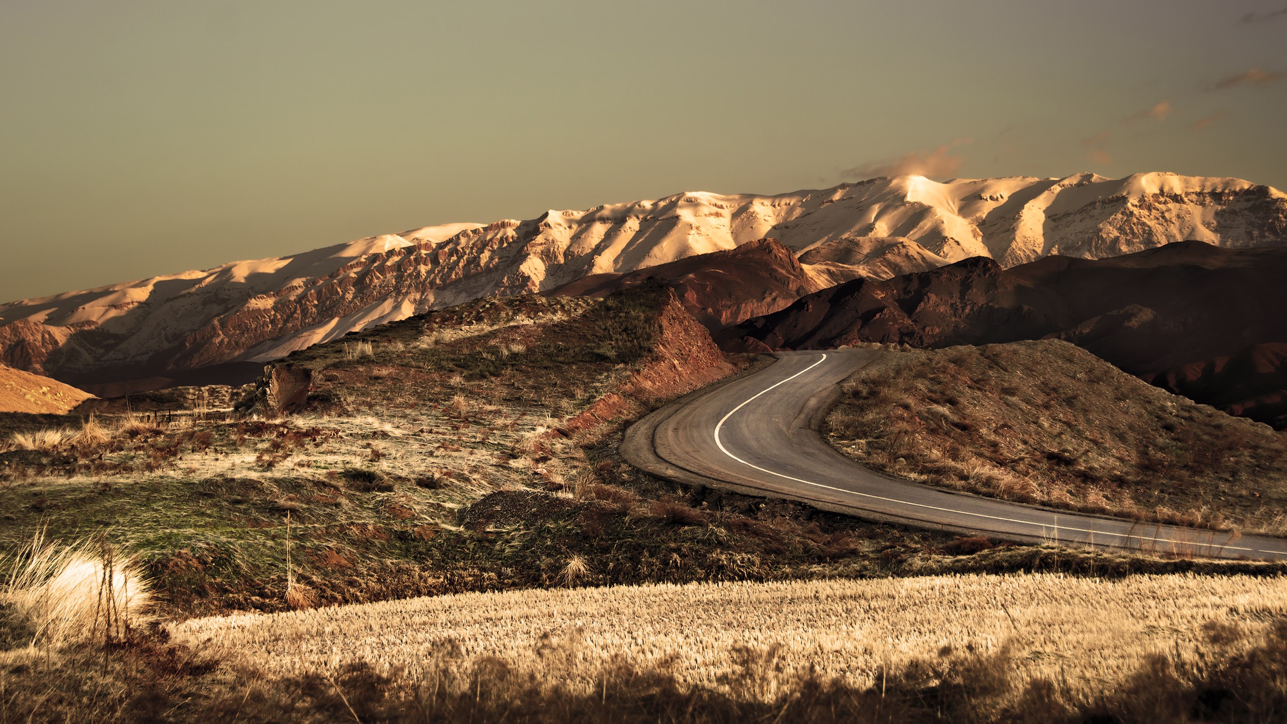 Winding road through a mountainous landscape HD Wallpaper