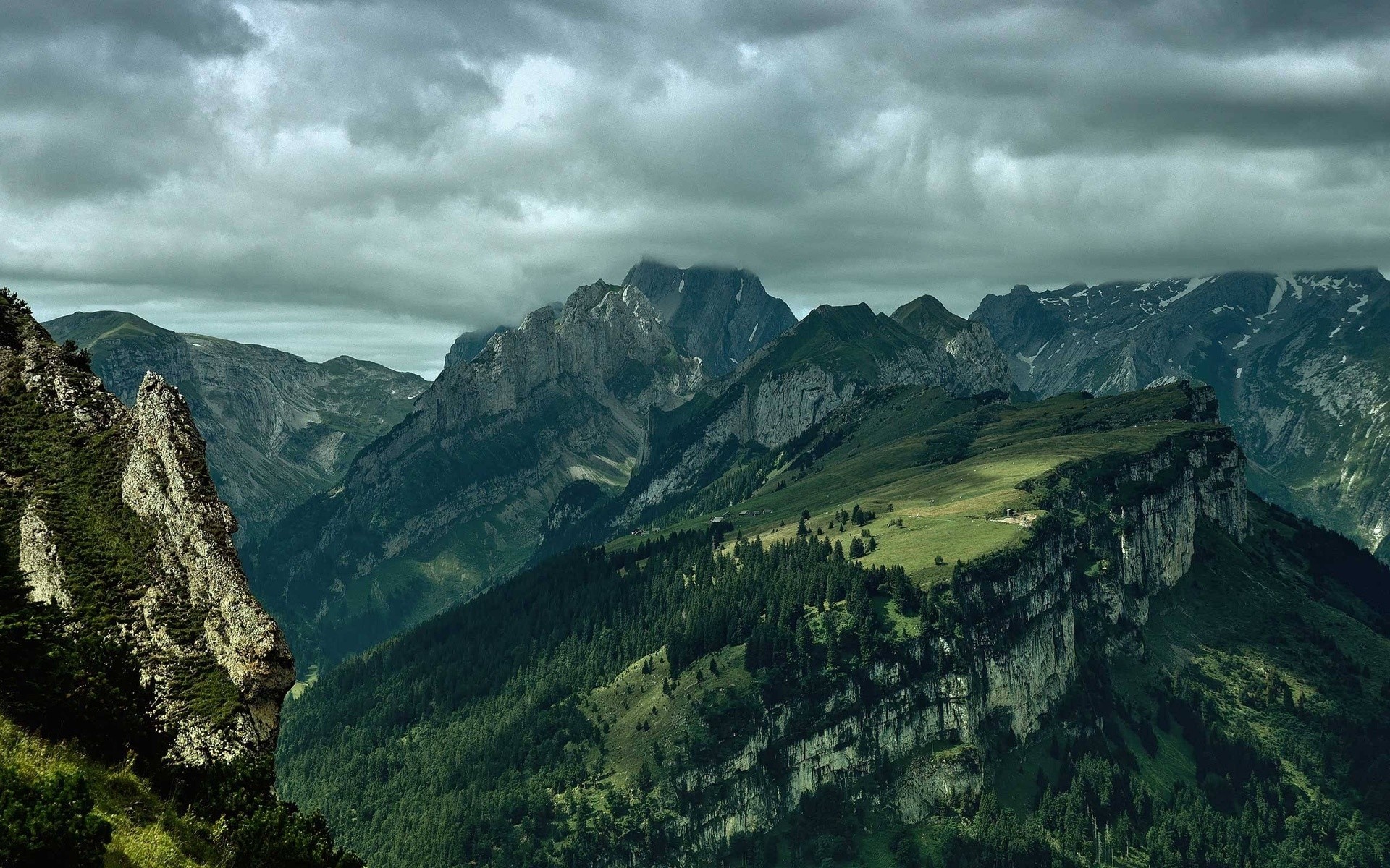Mountains and trees under a cloudy sky HD Wallpaper