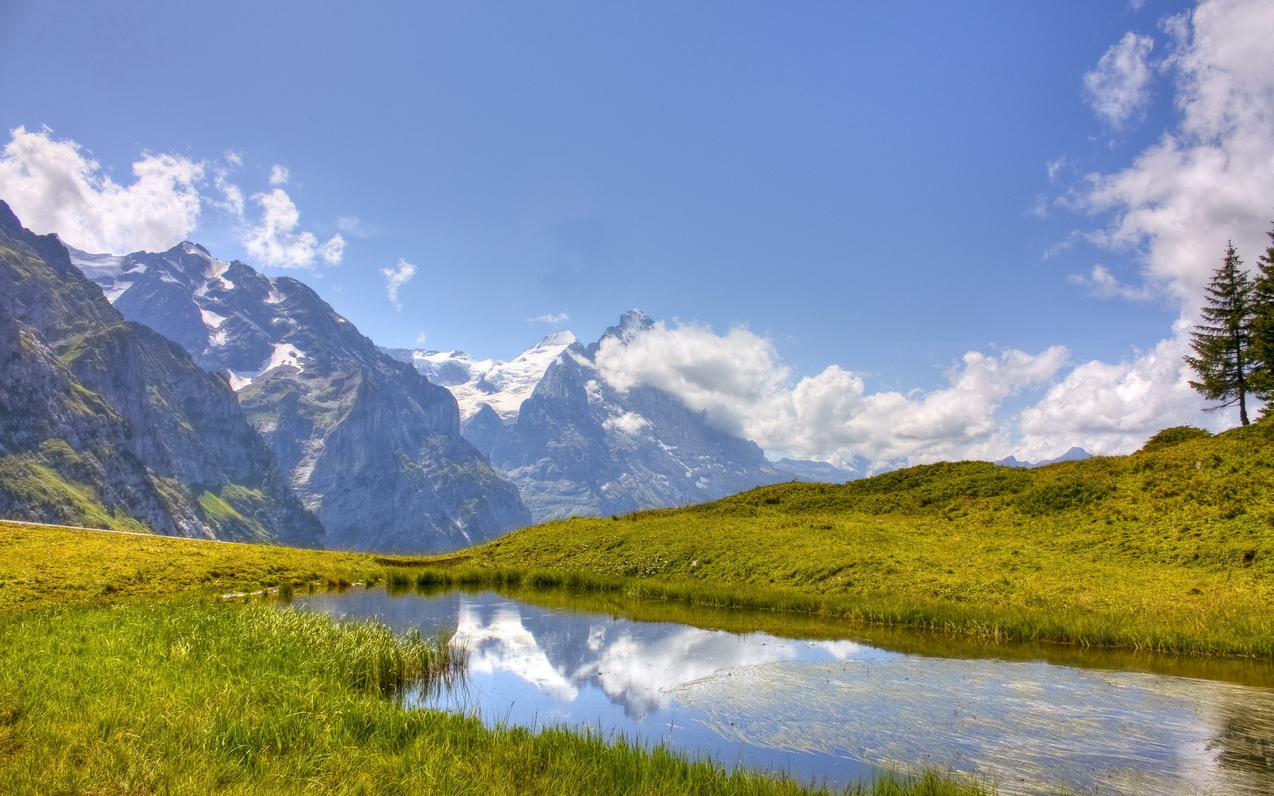 Mountains reflected in a calm lake with green hills HD Wallpaper
