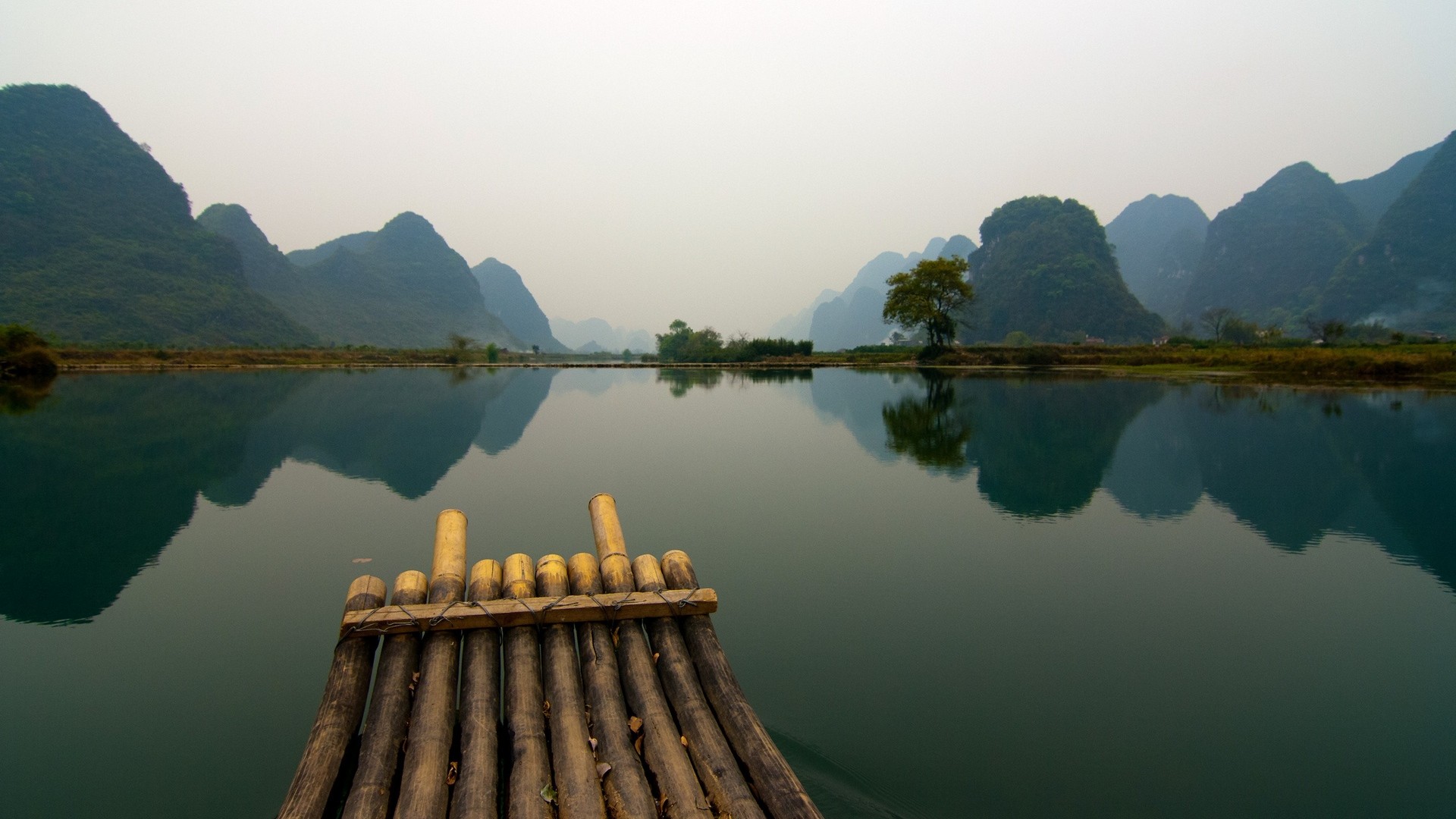 Bamboo raft on a calm lake with karst mountains reflection HD Wallpaper