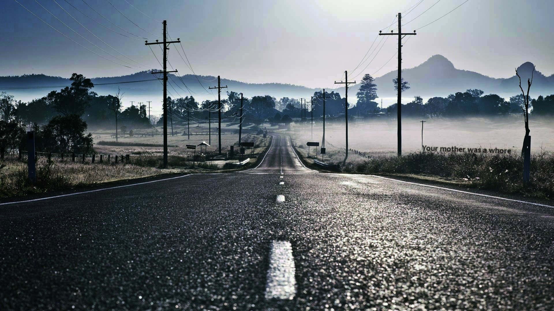 Road through a misty landscape with power lines HD Wallpaper