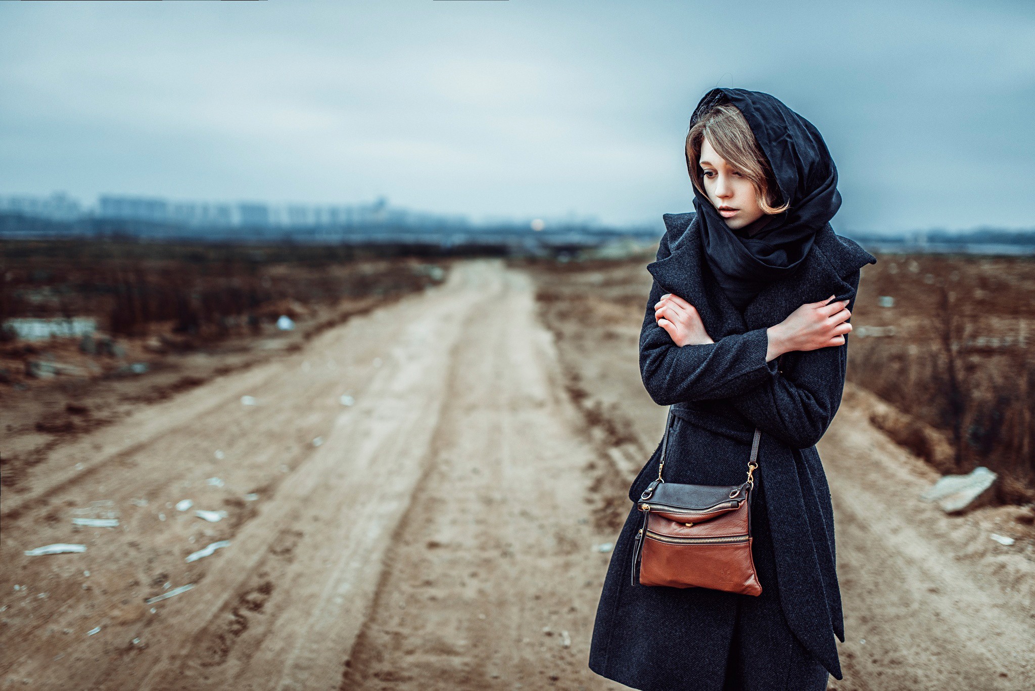 Woman in a dark coat and headscarf on a dirt road HD Wallpaper