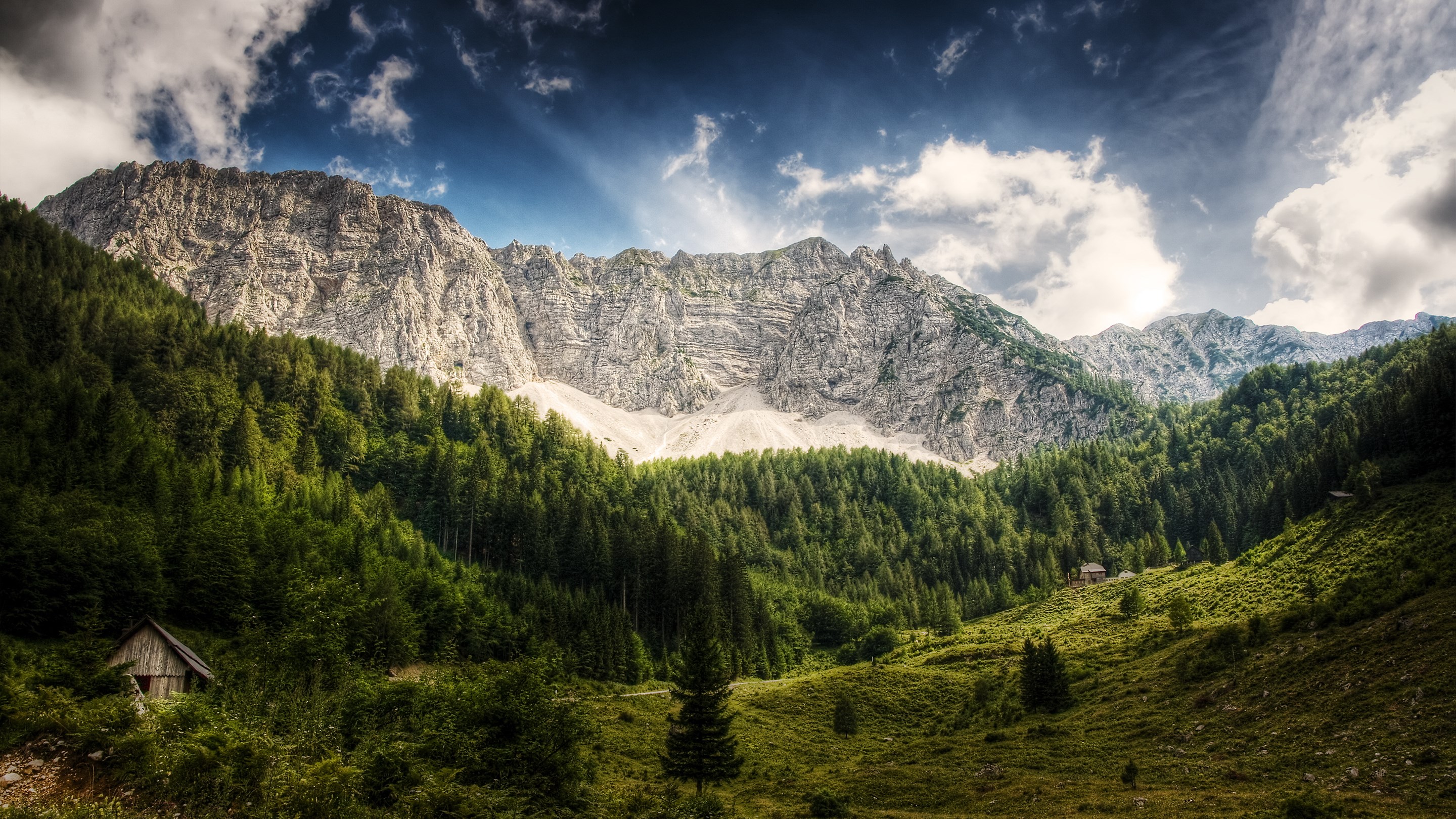 Wooden cabin in a mountain forest with dramatic clouds HD Wallpaper
